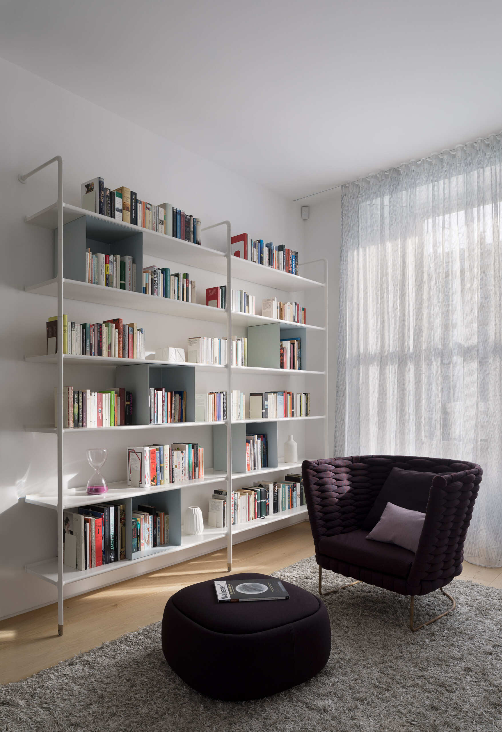A Victorian Kensington home begins with a calm sitting room featuring white open shelving and soft seating, setting the tone for a light filled interior.