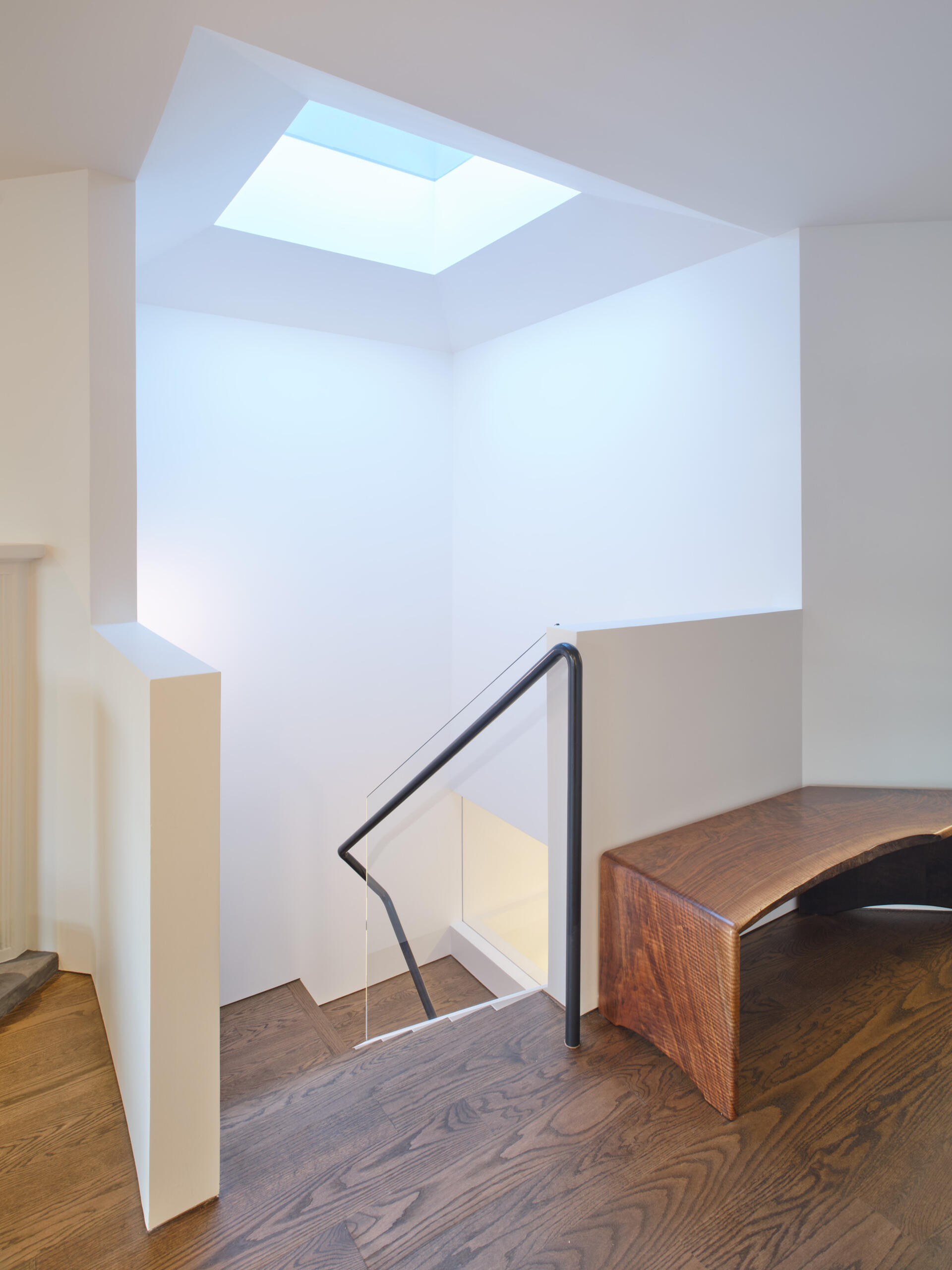 The original circulation did little to enhance light or connection between floors. Movement through the home felt secondary to the closed rooms it served.

The new central staircase transforms circulation into an architectural feature. A single piece glass guard maintains visual openness, while a sculptural metal handrail appears to float. Positioned beneath the skylight, the stair preserves sightlines and strengthens the sense of vertical continuity.
