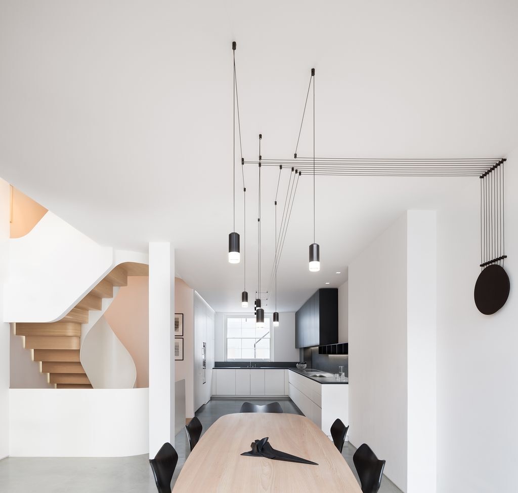 An open plan kitchen, dining, and living space contrasts dark cabinetry with white walls, designed for modern living and art display.