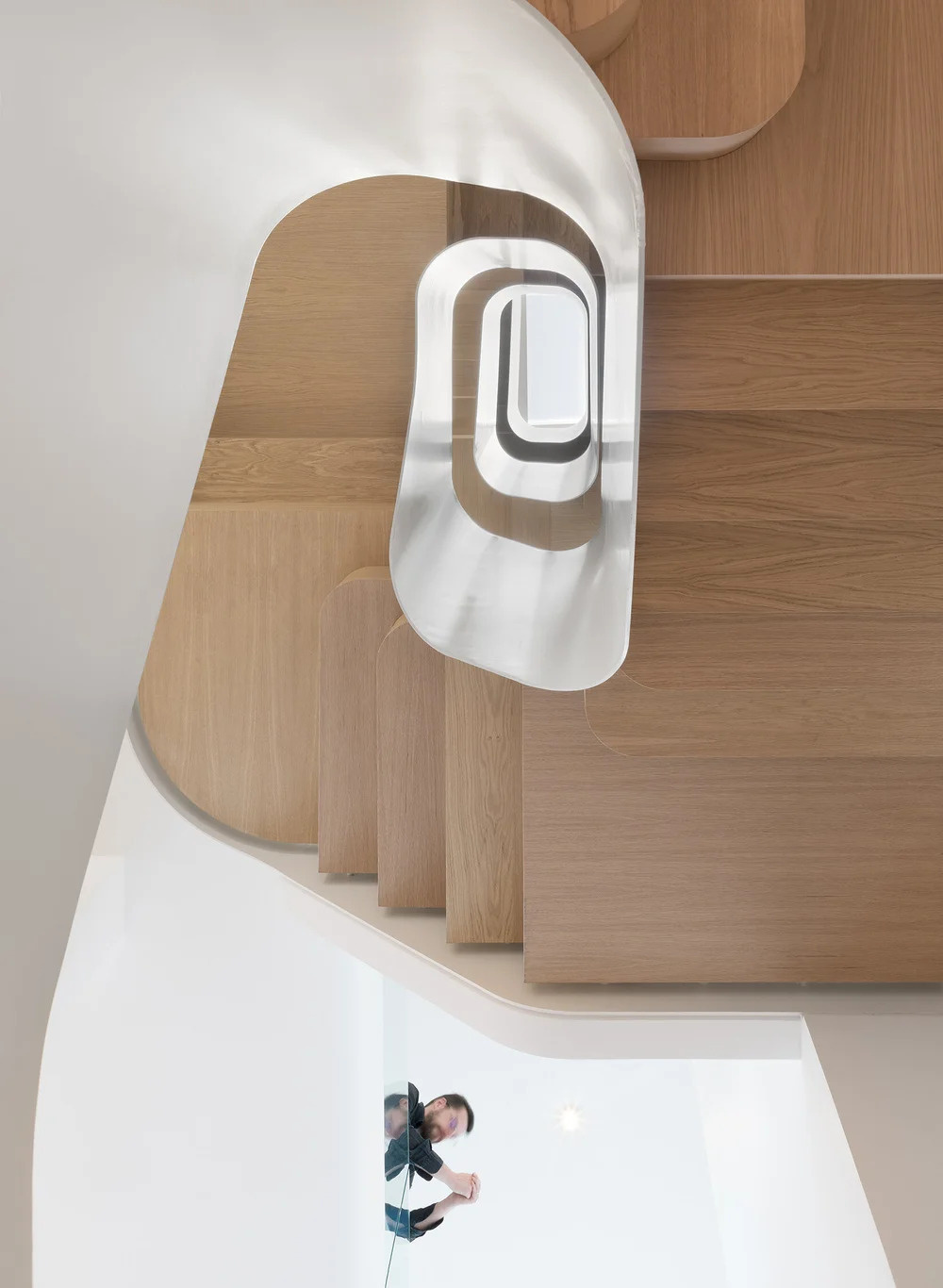 Wood stairs spiral through the home, acting as both circulation and a sculptural centerpiece that connects every level.