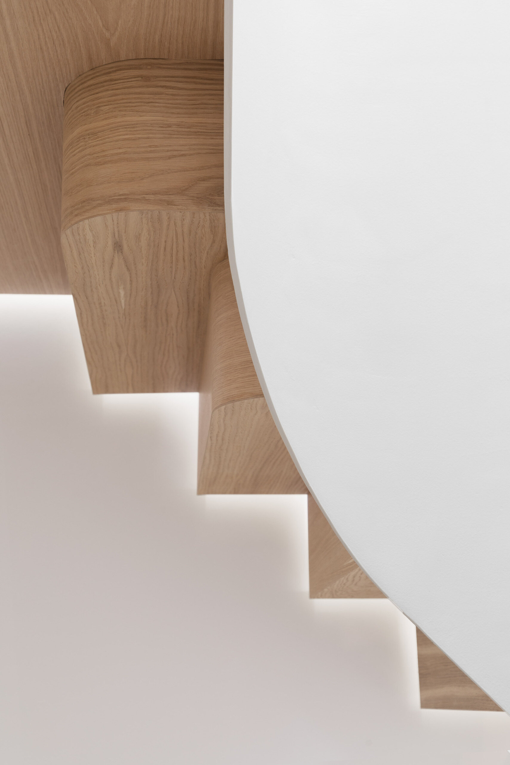 Wood stairs spiral through the home, acting as both circulation and a sculptural centerpiece that connects every level.
