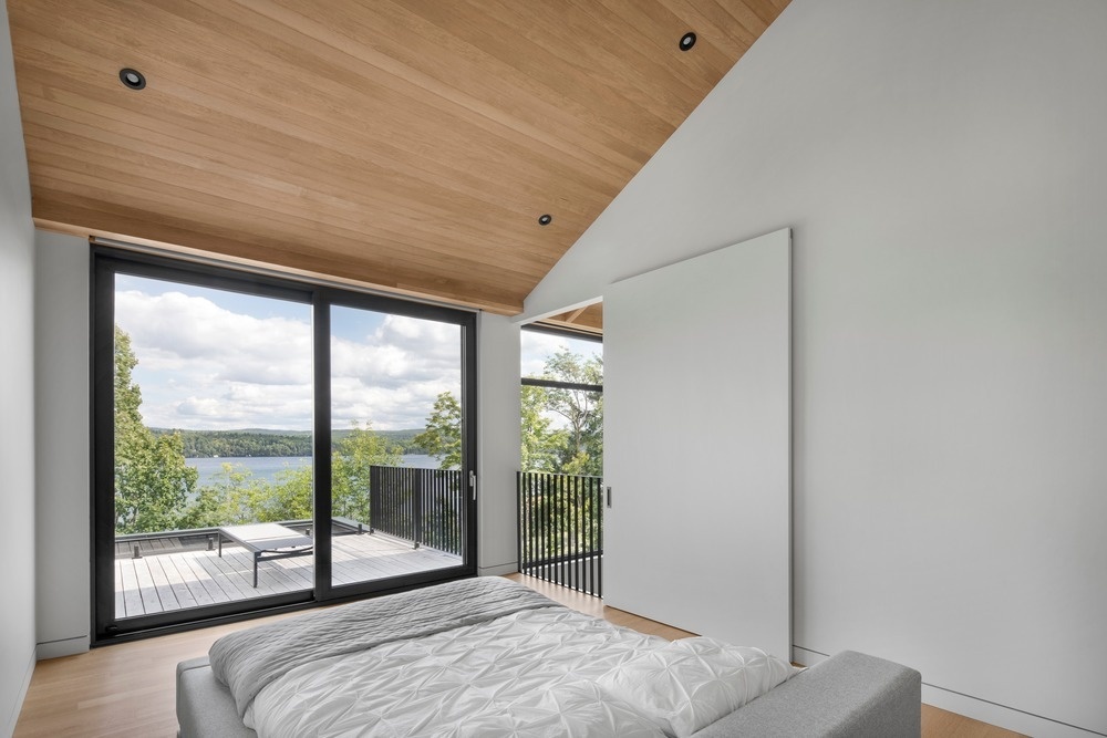 Minimal furniture and carefully placed windows allow this upstairs bedroom to focus entirely on tree canopies and water views.