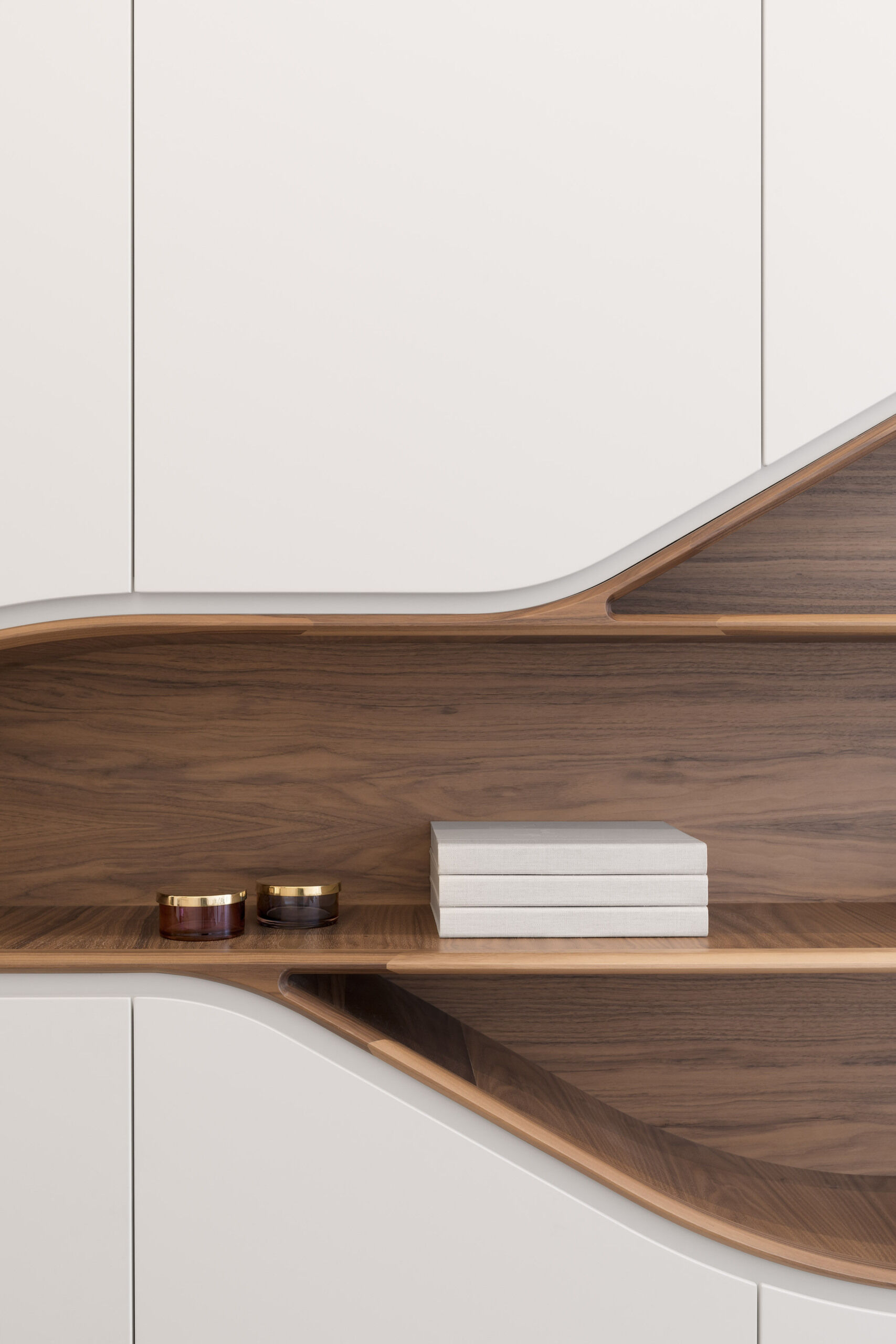 Minimalist white cabinetry frames a curved wood lined shelving feature, blending precision with warmth.