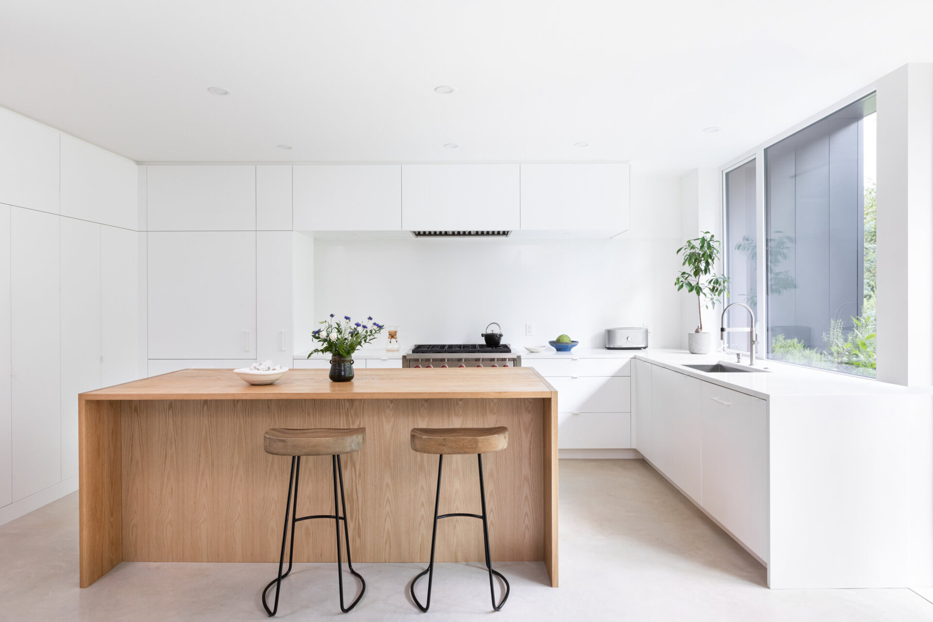 A wood island and seamless white cabinetry bring warmth and simplicity to this light filled modern kitchen.