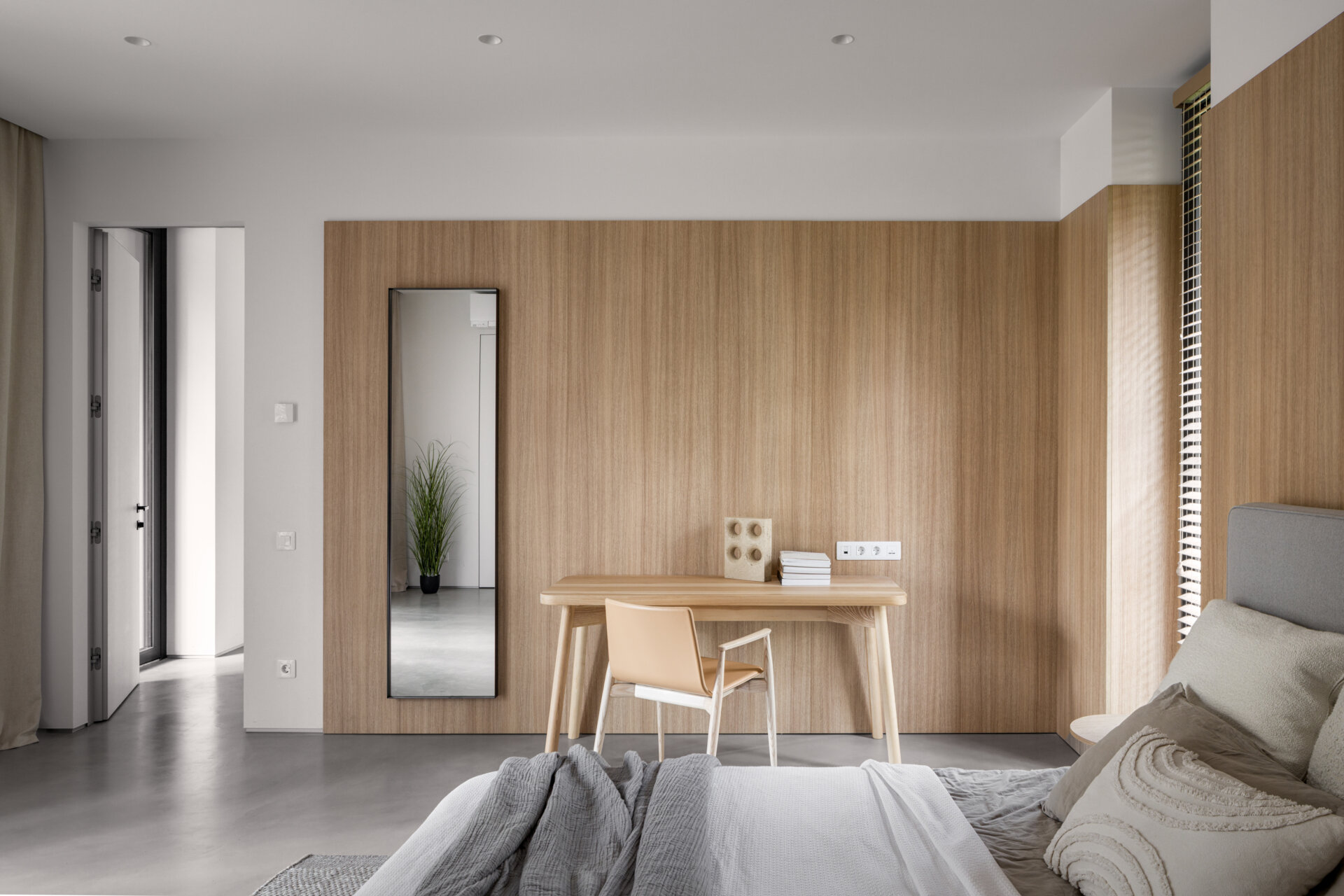 The primary bedroom, with its wood-lined walls, is located on the ground floor, offering direct access to the main living areas while maintaining privacy. It includes a walk-in wardrobe and a private bathroom.