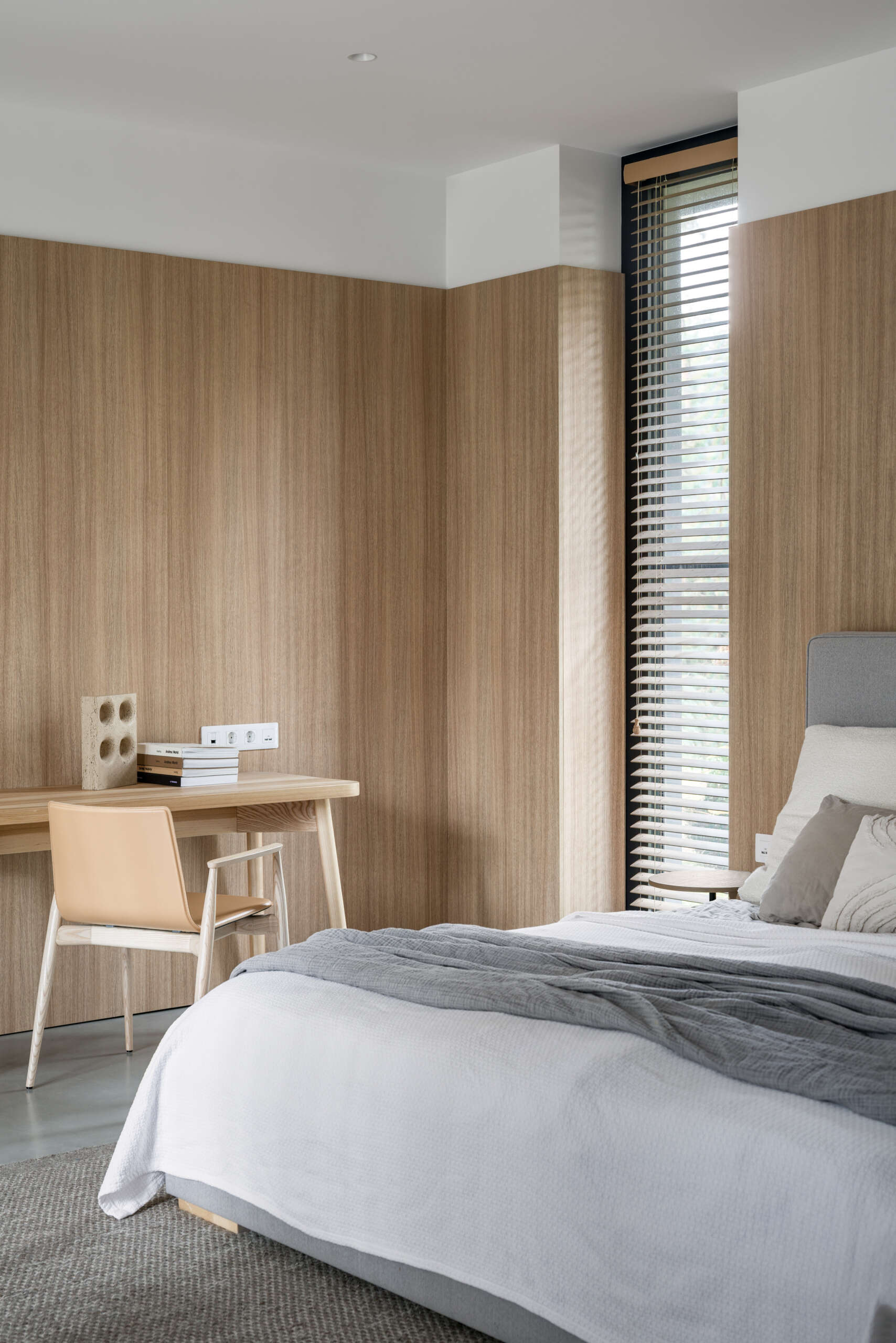 The primary bedroom, with its wood-lined walls, is located on the ground floor, offering direct access to the main living areas while maintaining privacy. It includes a walk-in wardrobe and a private bathroom.