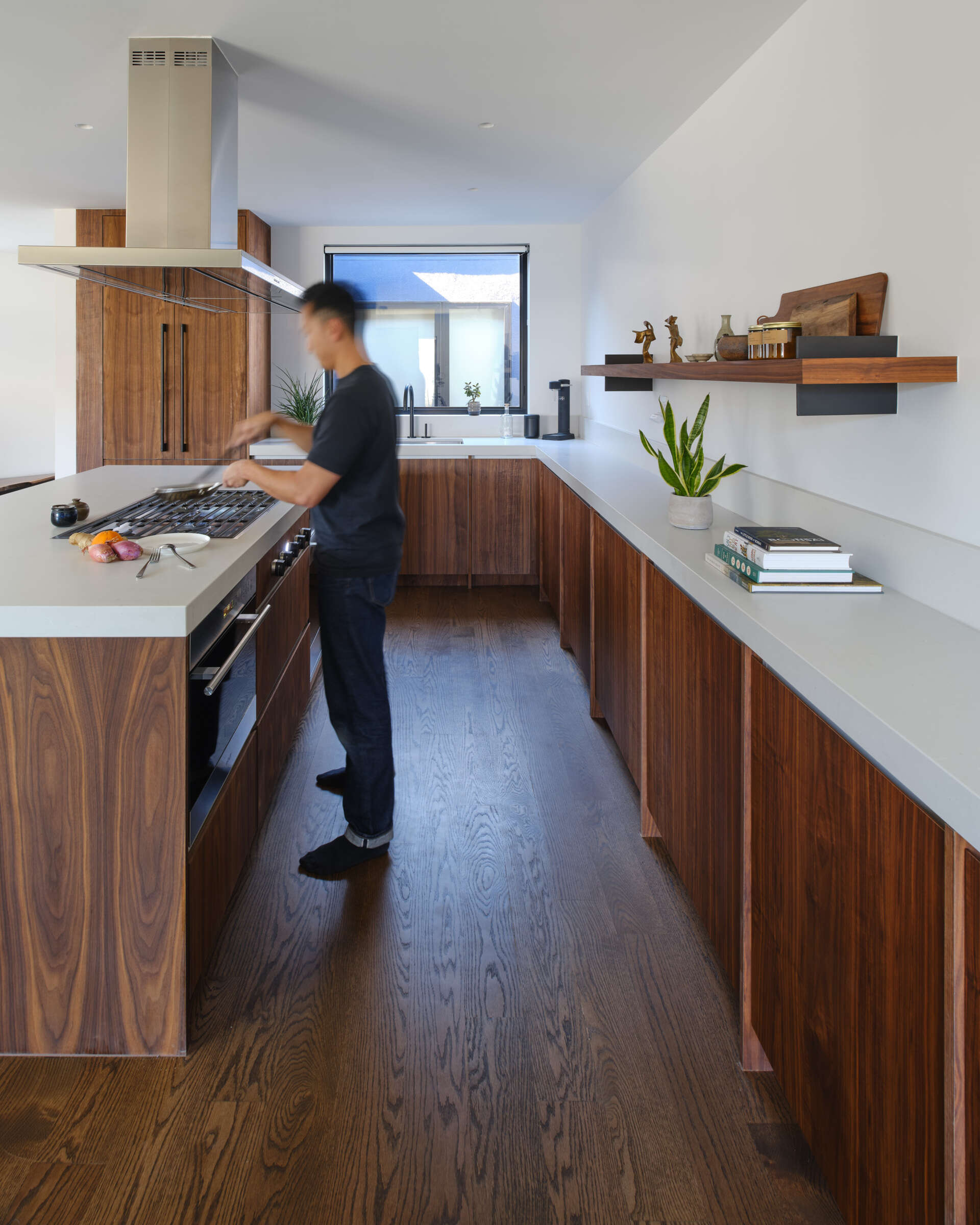 Before, the kitchen was part of the home’s dark and divided interior, lacking a strong relationship to the rest of the living spaces. After the renovation, the kitchen becomes a focal point. A walnut clad island folds geometrically upon itself, inspired by the home’s original 45 degree angled walls.