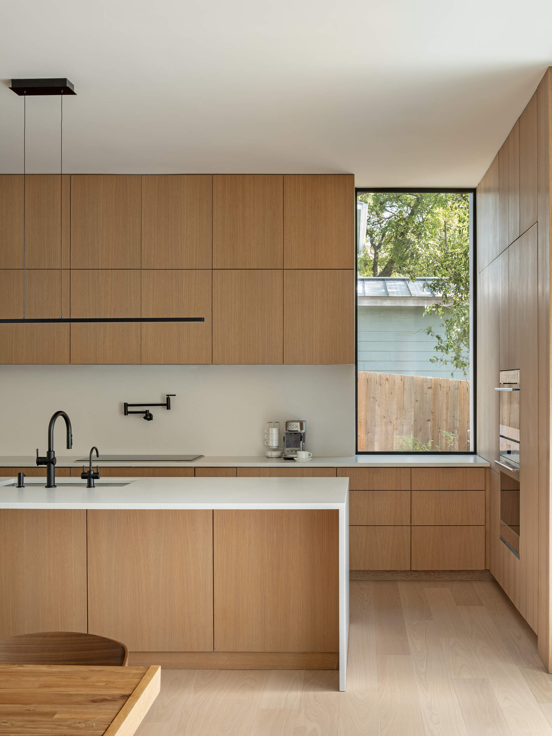 A clean, modern kitchen aligned with views through the house. Warm materials complement geometric lines, making a contemporary design feel inviting and lived-in.