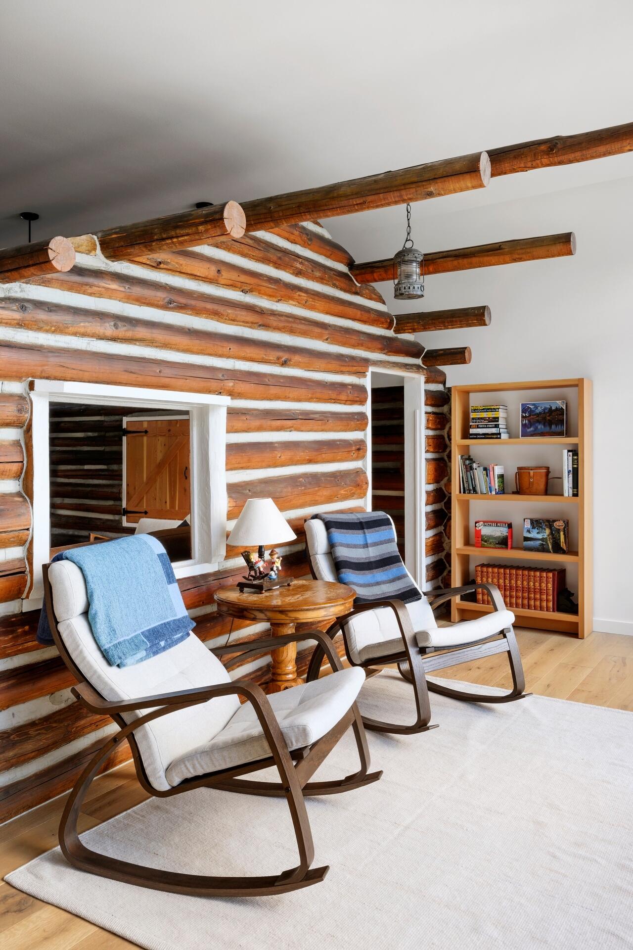 The restored log cabin now serves as the living room in this modern home, complete with original materials and subtle modern lighting.