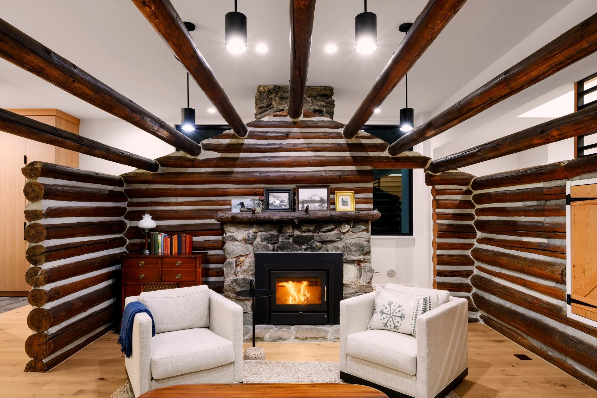 The restored log cabin now serves as the living room in this modern home, complete with original materials and subtle modern lighting.