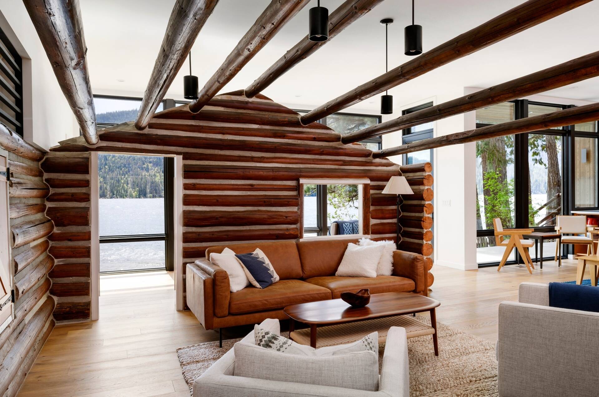 The restored log cabin now serves as the living room in this modern home, complete with original materials and subtle modern lighting.
