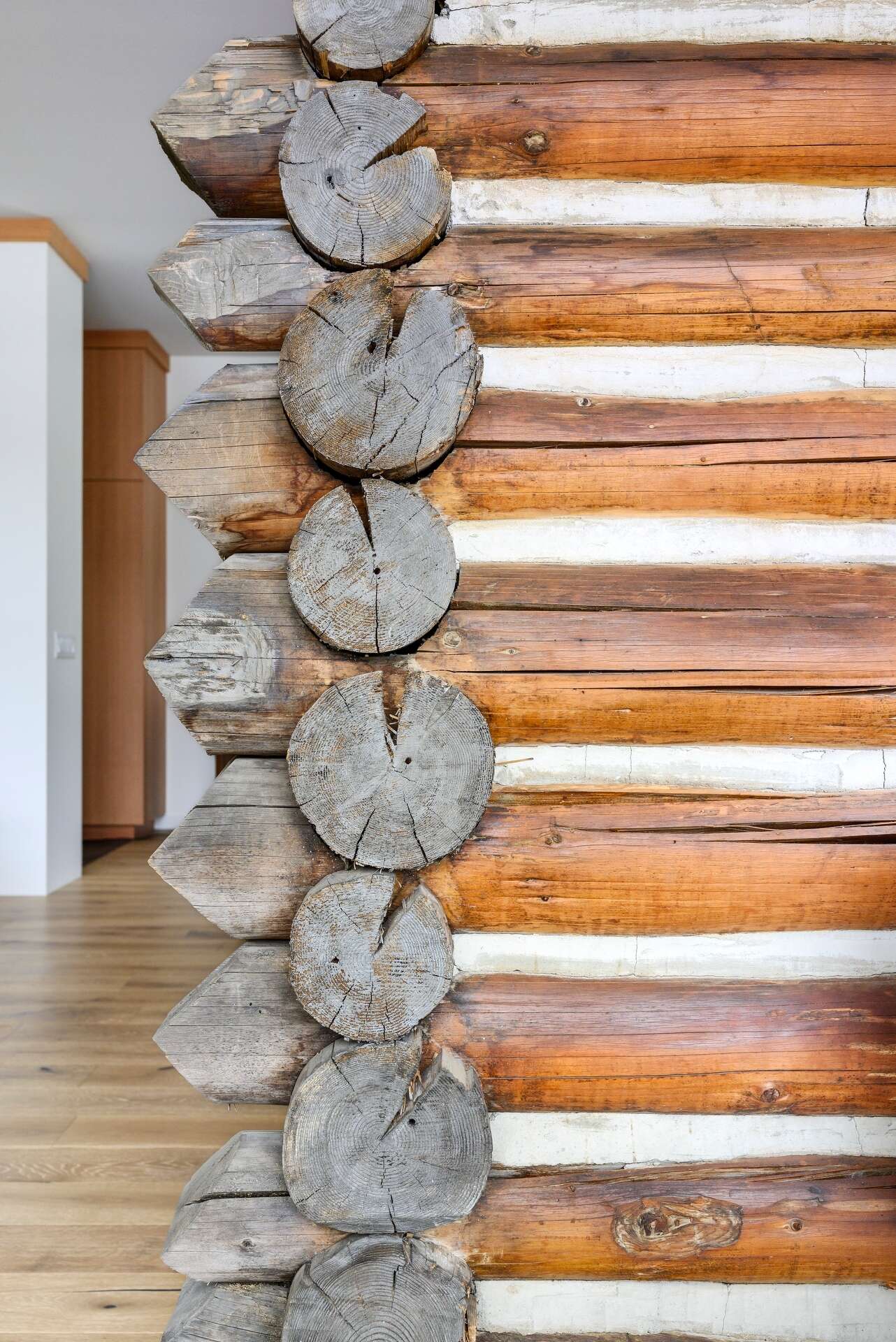 The restored log cabin now serves as the living room in this modern home, complete with original materials and subtle modern lighting.