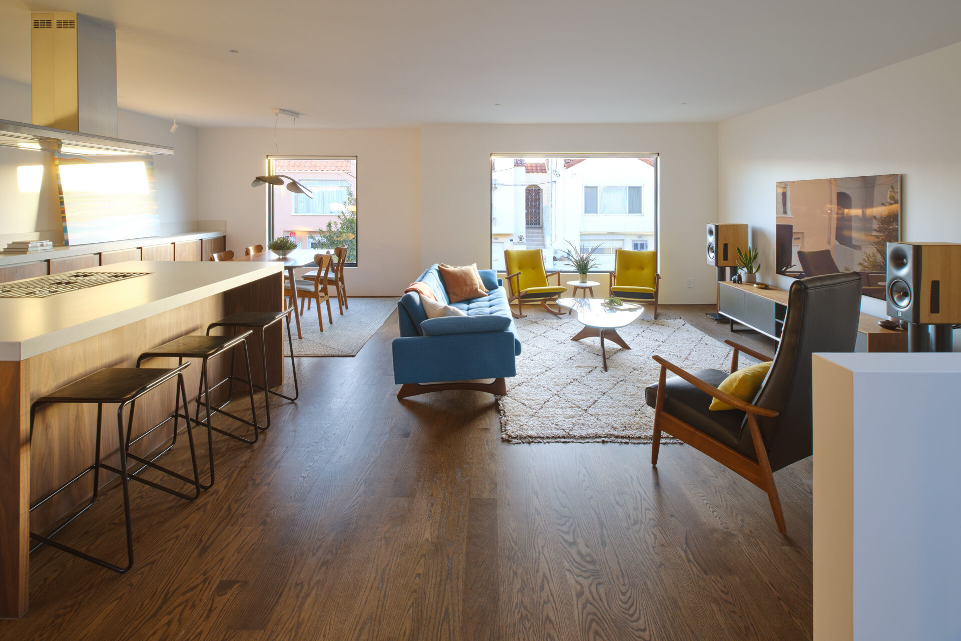 Previously, living spaces were segmented, cutting off visual connections and natural light. The layout felt constrained by its compartmentalized plan. Now, the living and dining areas unfold within the open upper level. Refinished original oak floors in a deeper tone ground the space, complemented by walnut millwork that adds warmth without overwhelming the volume.