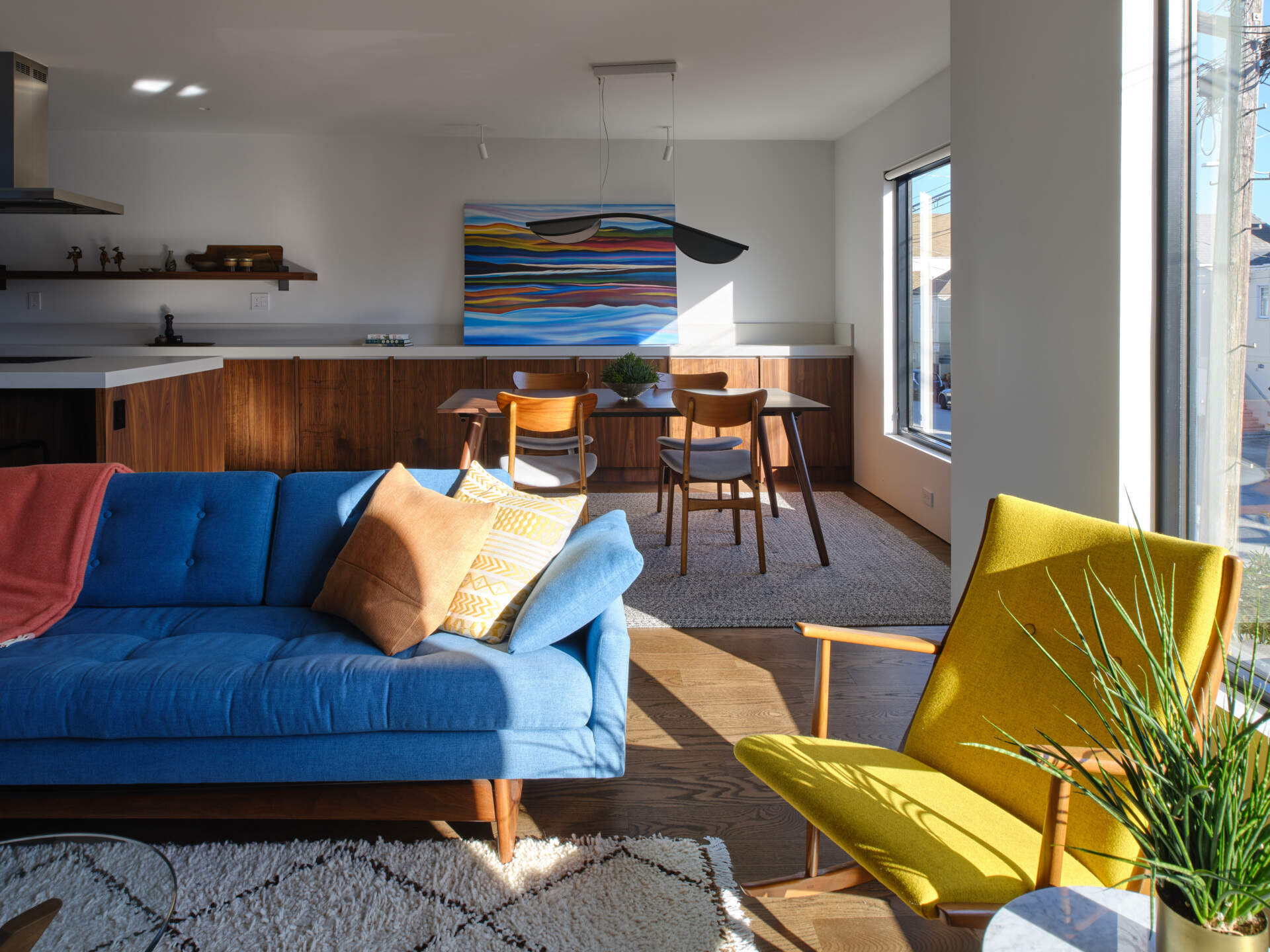 Previously, living spaces were segmented, cutting off visual connections and natural light. The layout felt constrained by its compartmentalized plan. Now, the living and dining areas unfold within the open upper level. Refinished original oak floors in a deeper tone ground the space, complemented by walnut millwork that adds warmth without overwhelming the volume.