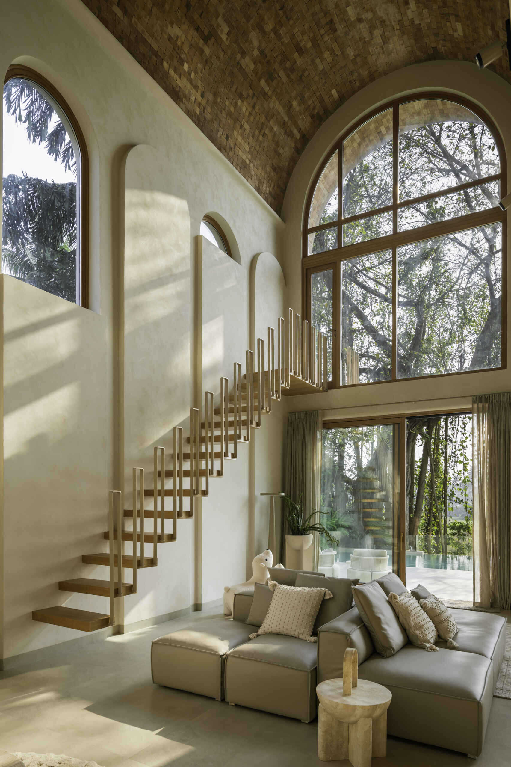 A compact staircase rises to a tiny balcony designed for one, creating a quiet vertical pause within the vaulted living area.