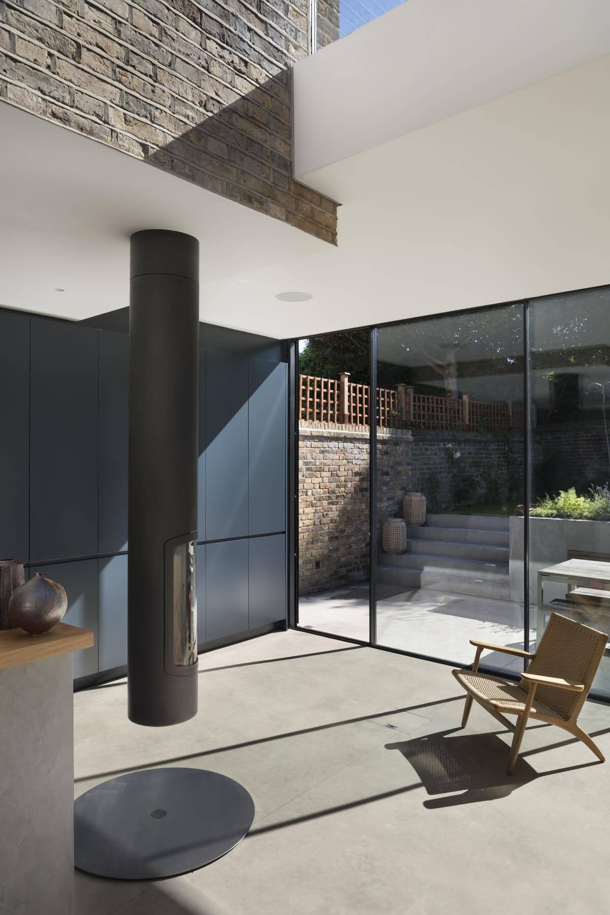 Floor to ceiling sliding doors and a suspended pivoting fireplace complete this light filled London extension with seamless access to a secluded garden.