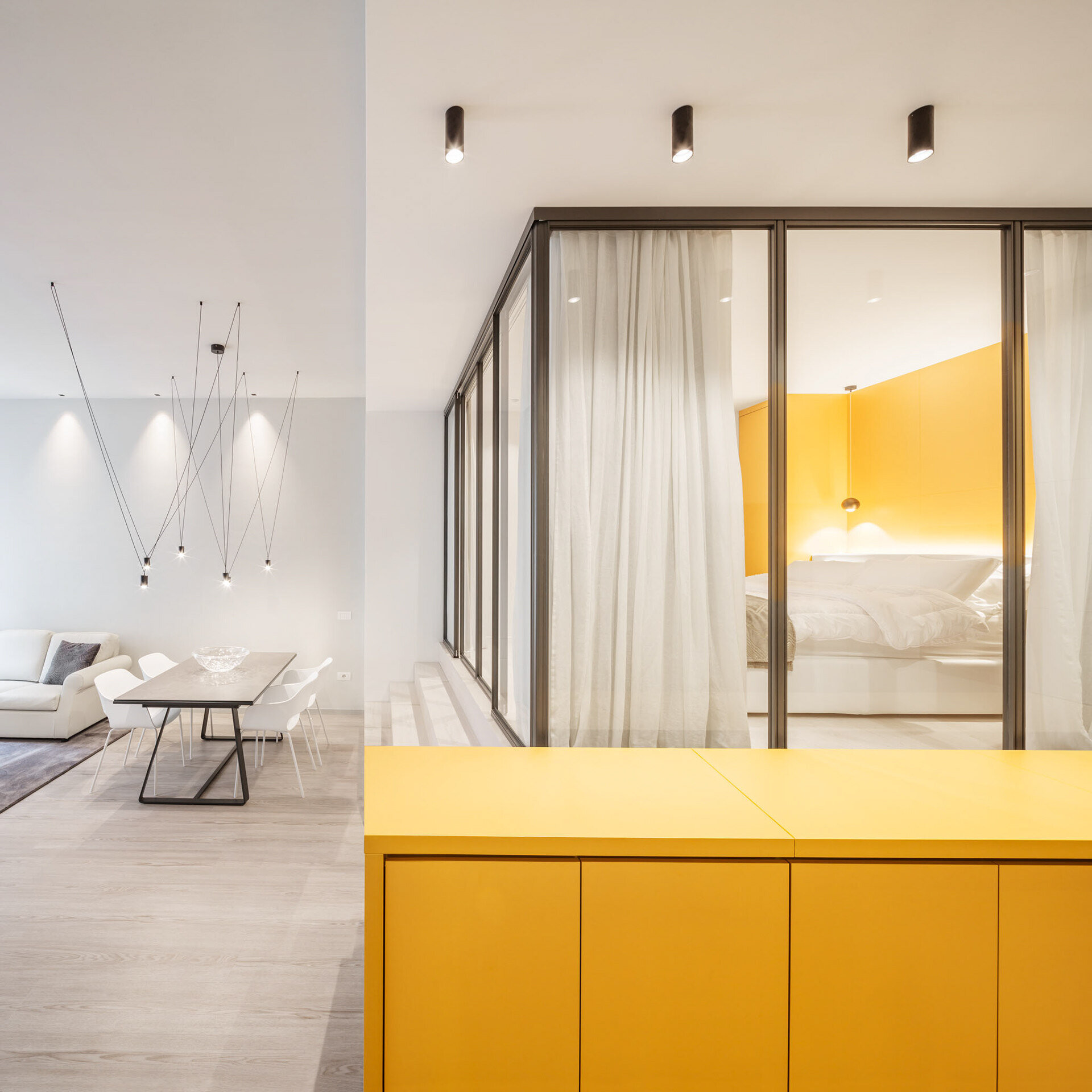 A minimalist dining and living area sits beside the kitchen and bedroom, finished with warm tones and subtle gold details.