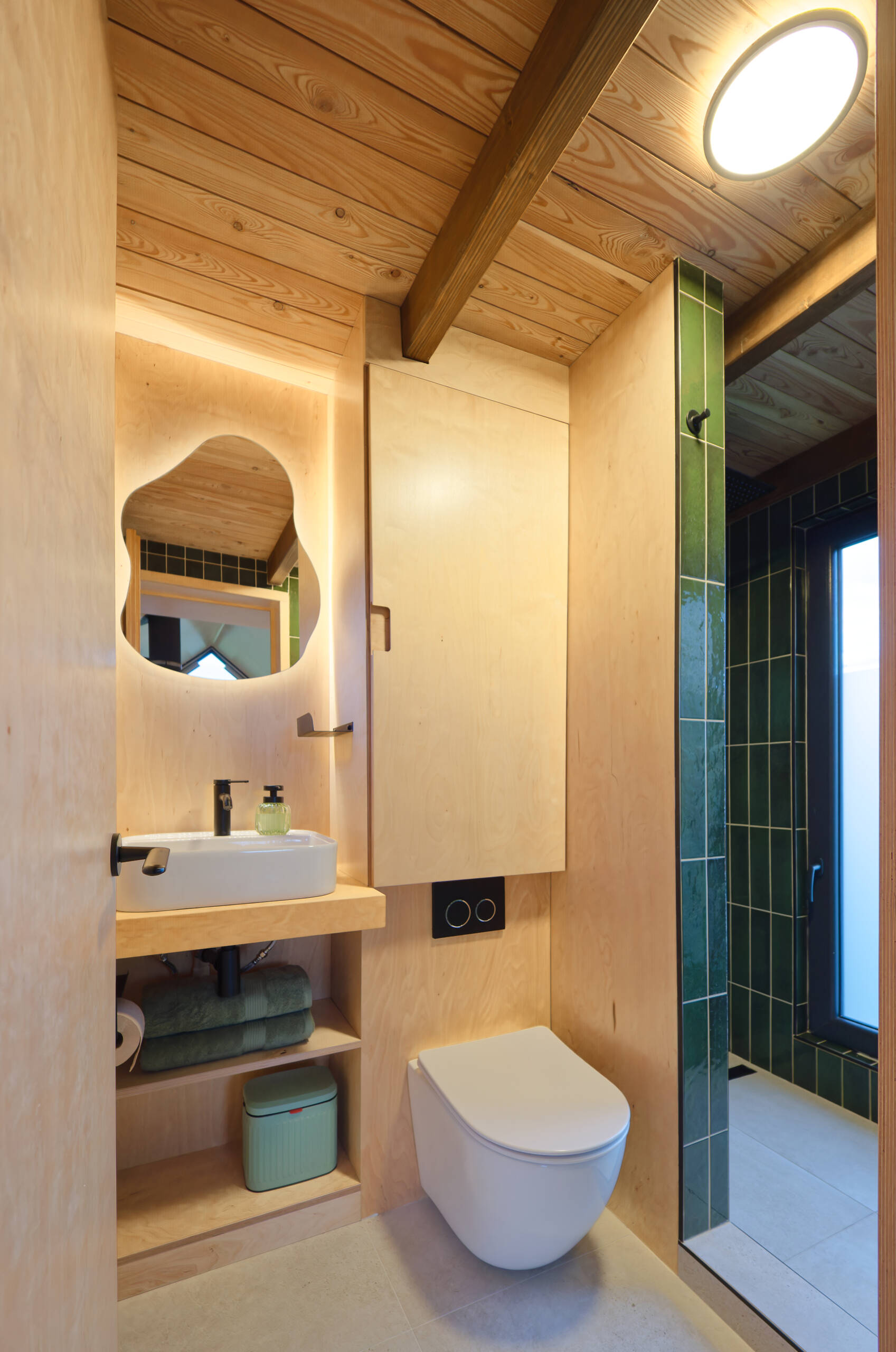 Light birch plywood, a visible gabled roof, and a striking trapezoidal window make this micro cabin interior feel surprisingly spacious. Included in the cabin is a sleeping area, lounge, kitchen, loft, and bathroom.