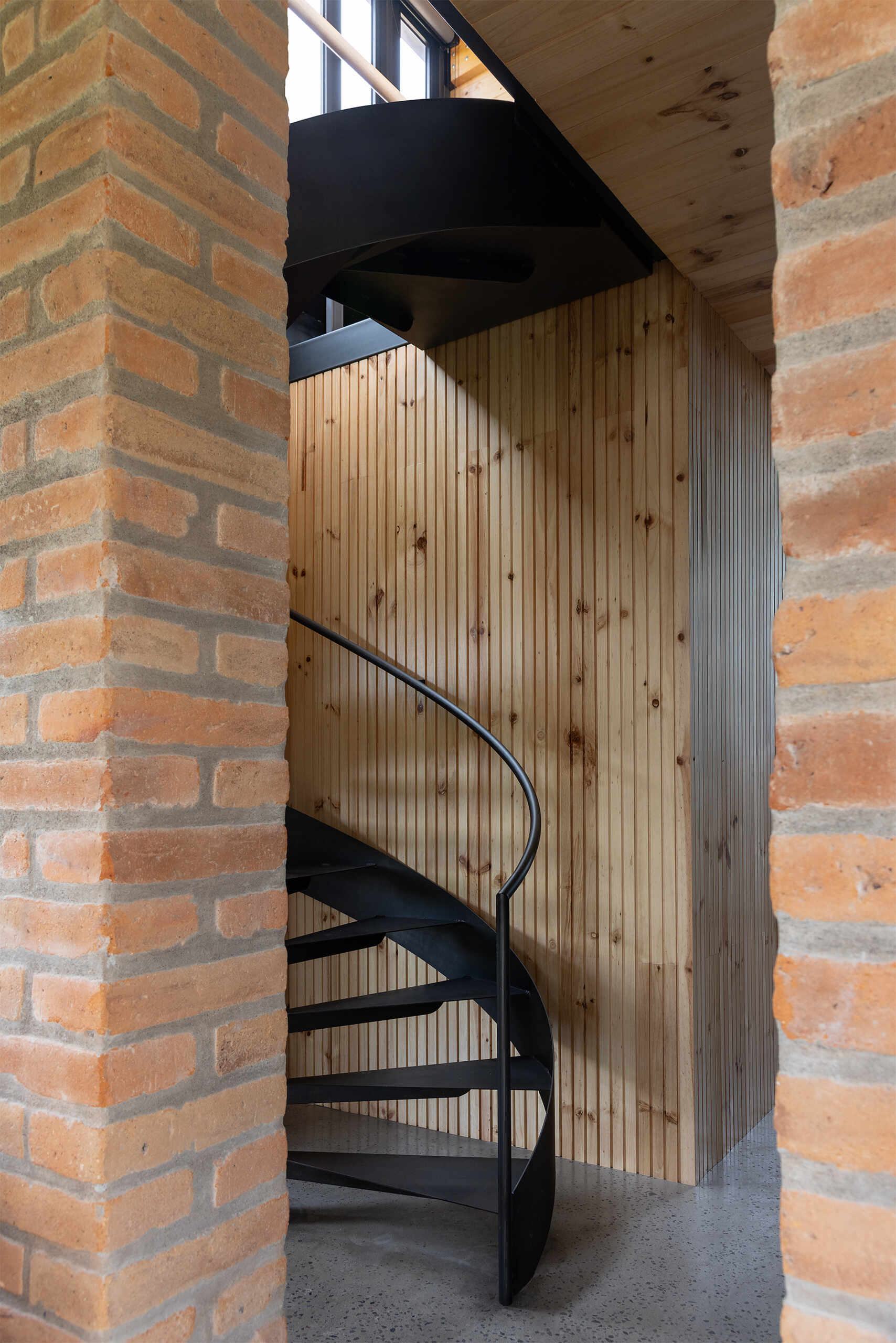 A sculptural stair connects the main living level to the visitor-focused lower floor, reinforcing the home’s vertical organization.