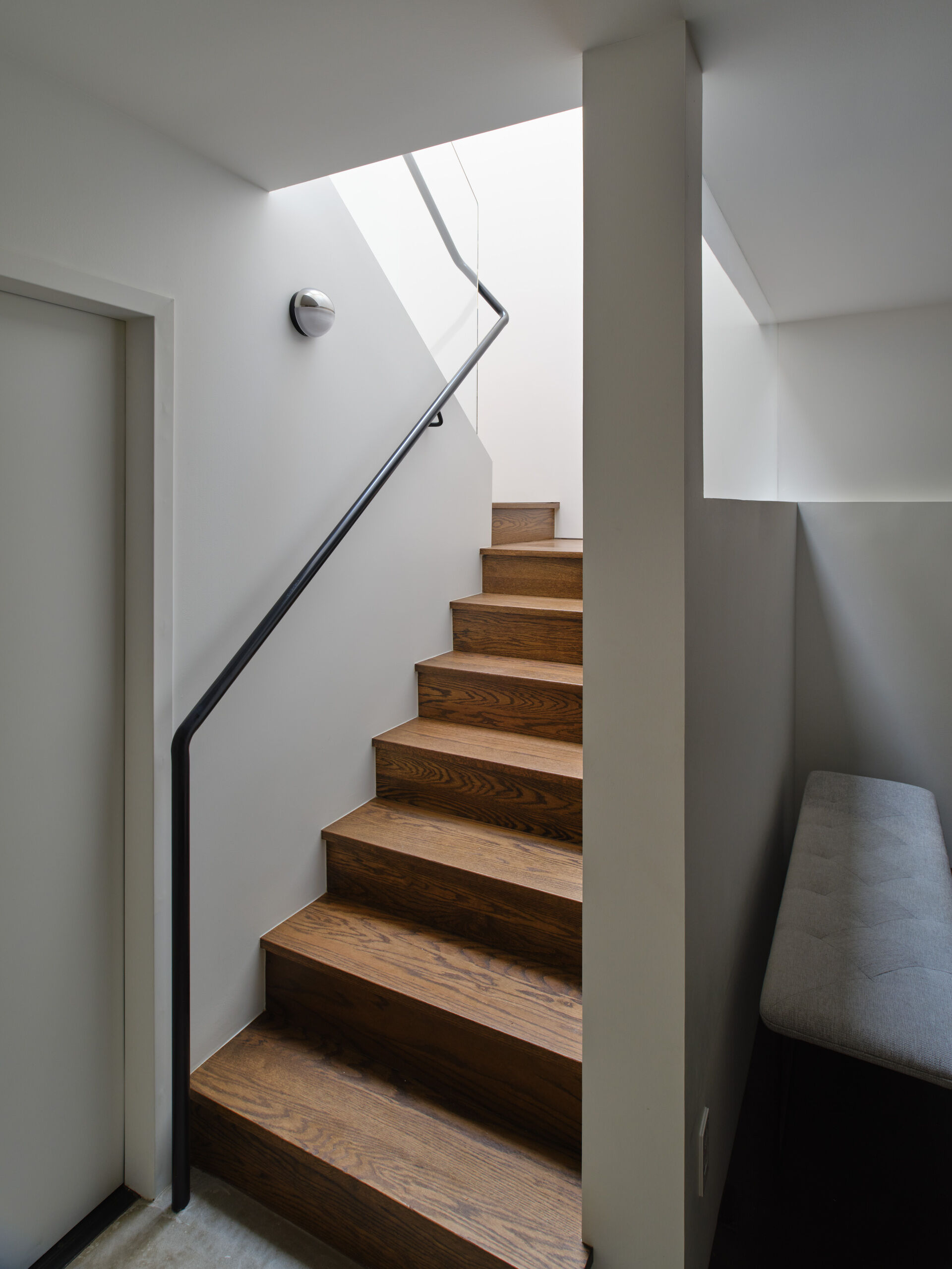 The original circulation did little to enhance light or connection between floors. Movement through the home felt secondary to the closed rooms it served.

The new central staircase transforms circulation into an architectural feature. A single piece glass guard maintains visual openness, while a sculptural metal handrail appears to float. Positioned beneath the skylight, the stair preserves sightlines and strengthens the sense of vertical continuity.