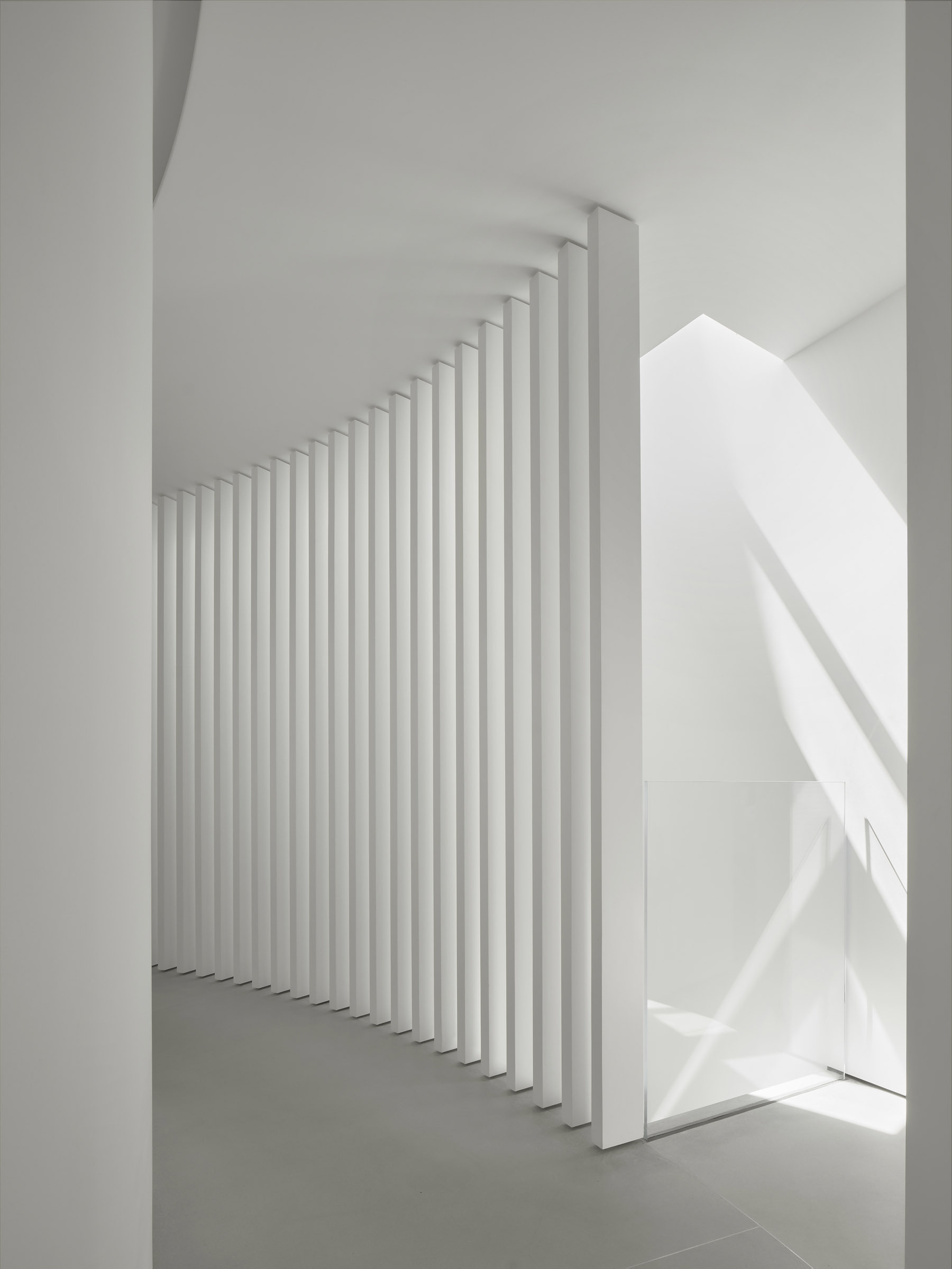 A concentric hallway wraps around the kitchen, guiding movement through the home while separating shared spaces from private rooms.