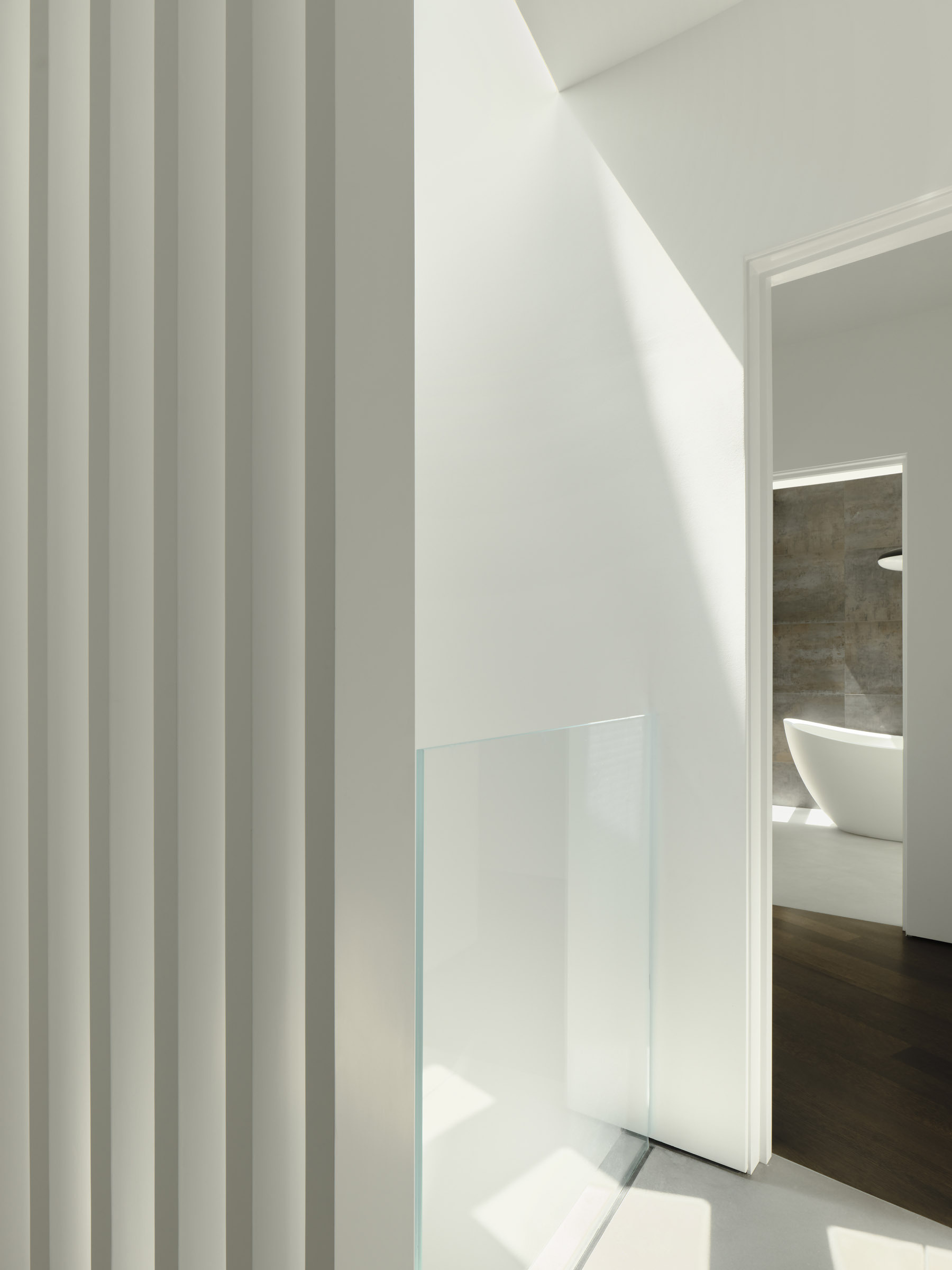 A concentric hallway wraps around the kitchen, guiding movement through the home while separating shared spaces from private rooms.