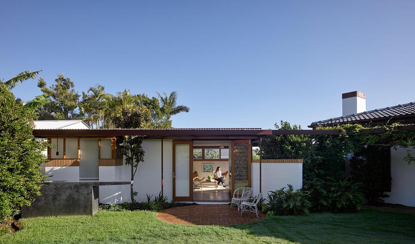 A double-hinged glass door opens the studio to the backyard, bringing in air and extending the workspace outdoors.