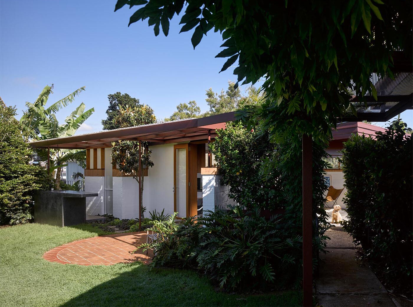 A double-hinged glass door opens the studio to the backyard, bringing in air and extending the workspace outdoors.