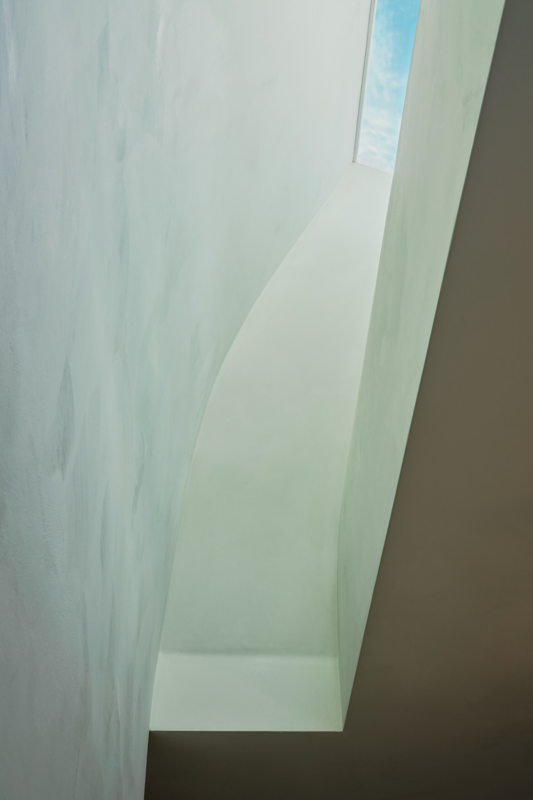 In the bedroom, a curved wall and skylight bring in shifting natural light that changes the mood throughout the day.