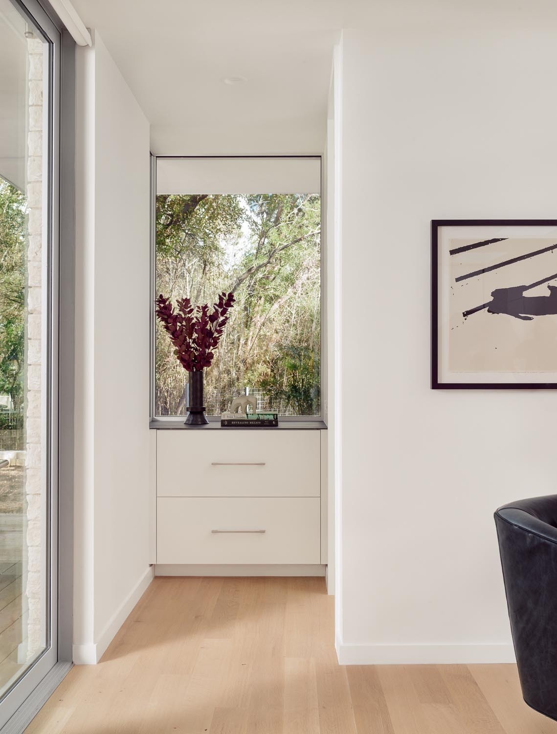 A built-in dresser and a bright white bathroom with a skylight and glass shower screen complete the interior of this small Austin guest house.