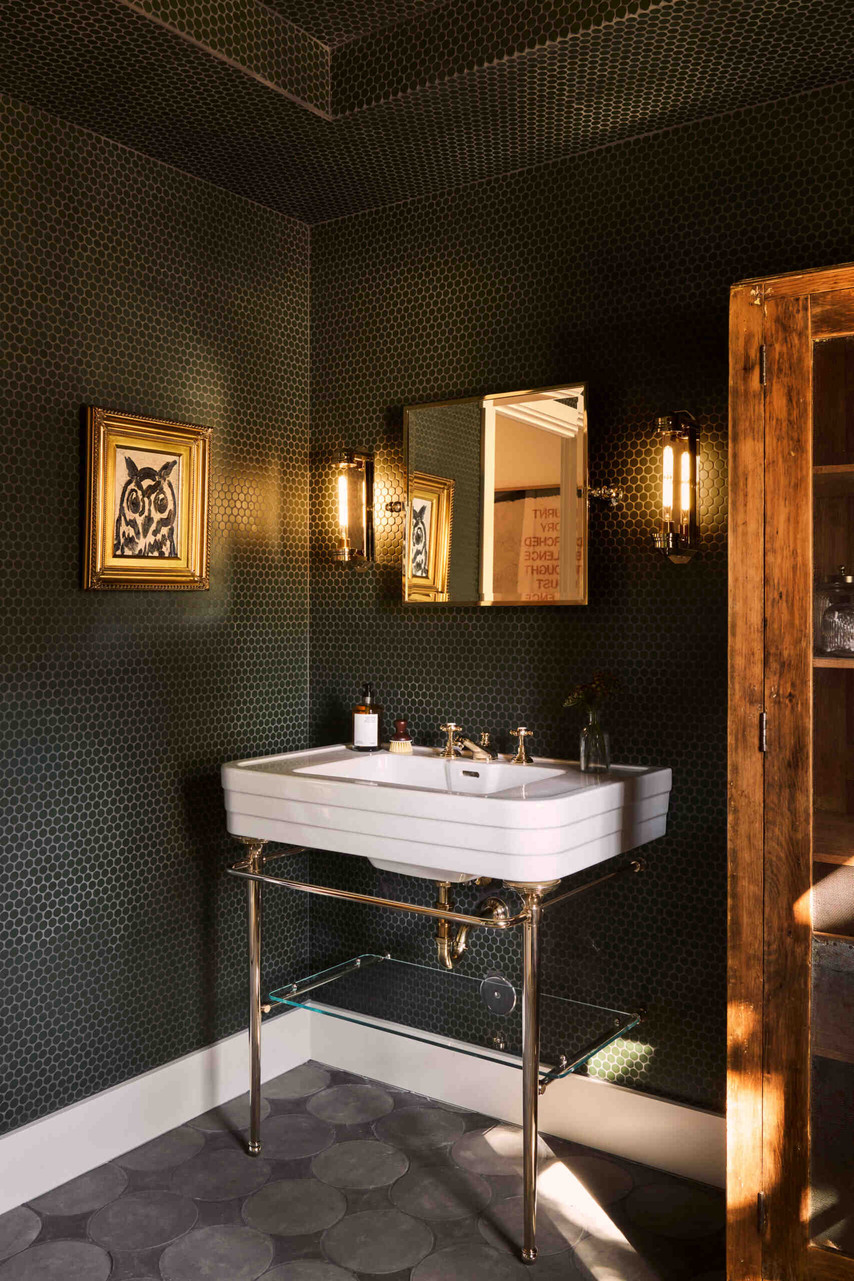 In the bathroom, black penny tiles create a bold, graphic look with simple repetition and strong visual rhythm.