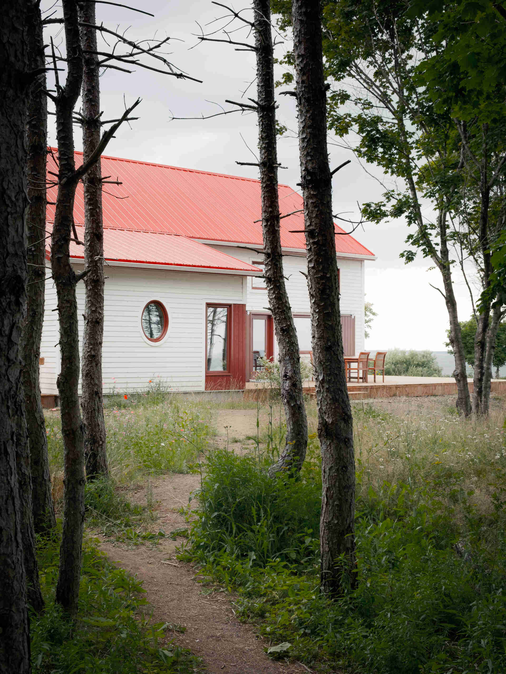 Inspirada en las históricas chozas de pesca, esta casa moderna toma la forma de un cobertizo simple, que utiliza madera, metal y atrevidas contraventanas rojas para crear una apariencia llamativa pero familiar.