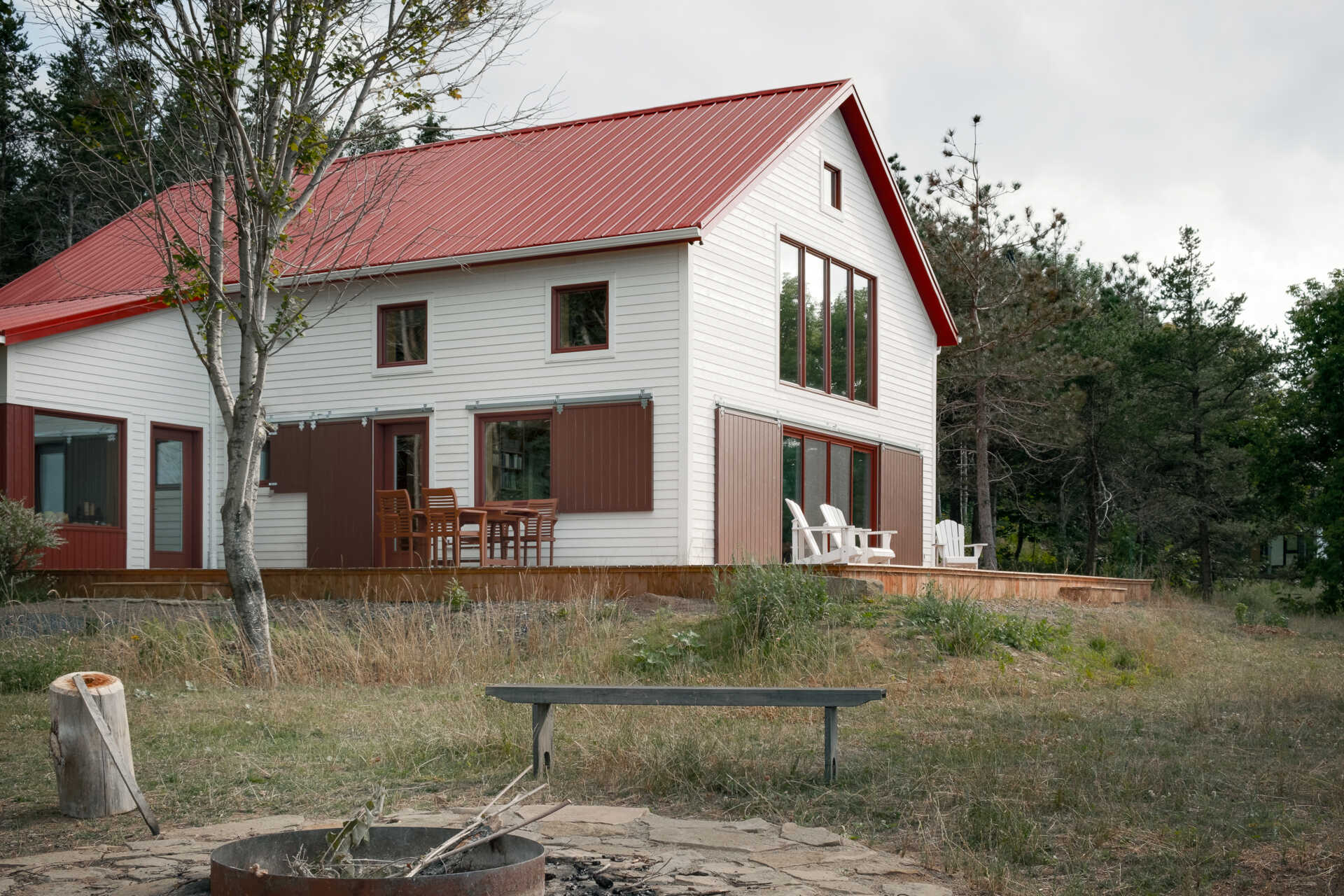 Inspirada en las históricas chozas de pesca, esta casa moderna toma la forma de un cobertizo simple, que utiliza madera, metal y atrevidas contraventanas rojas para crear una apariencia llamativa pero familiar.