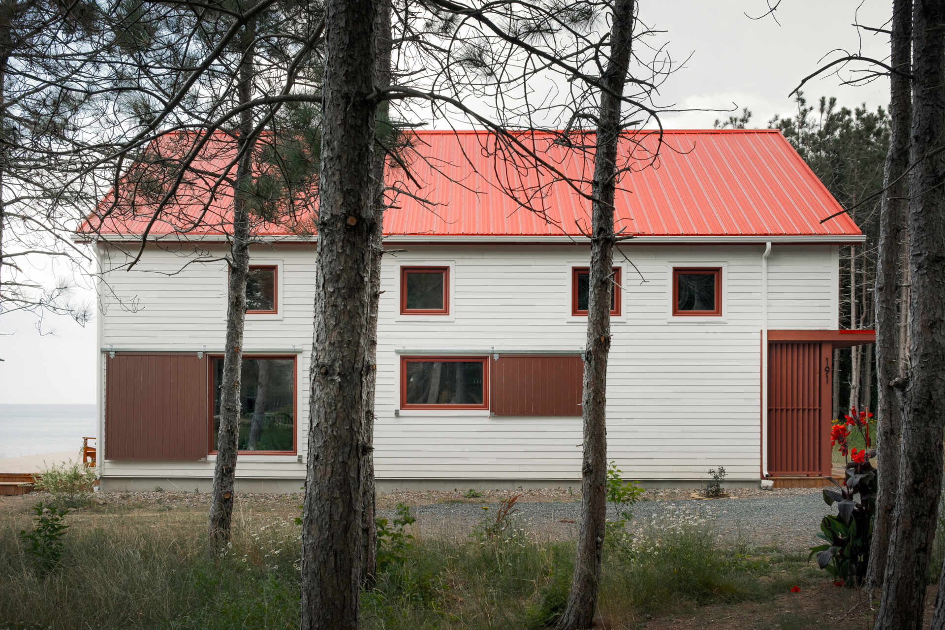 Inspirada en las históricas chozas de pesca, esta casa moderna toma la forma de un cobertizo simple, que utiliza madera, metal y atrevidas contraventanas rojas para crear una apariencia llamativa pero familiar.
