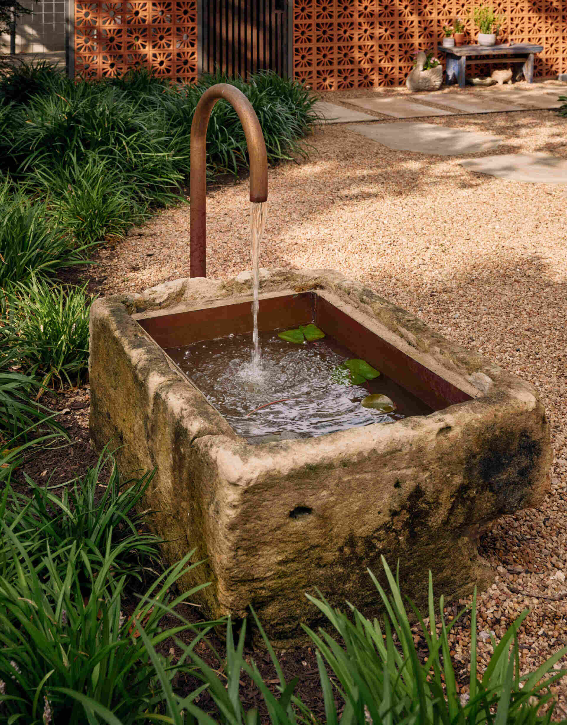 In the backyard, terraced planters and native landscaping create layered outdoor spaces leading to a terracotta-toned carport.