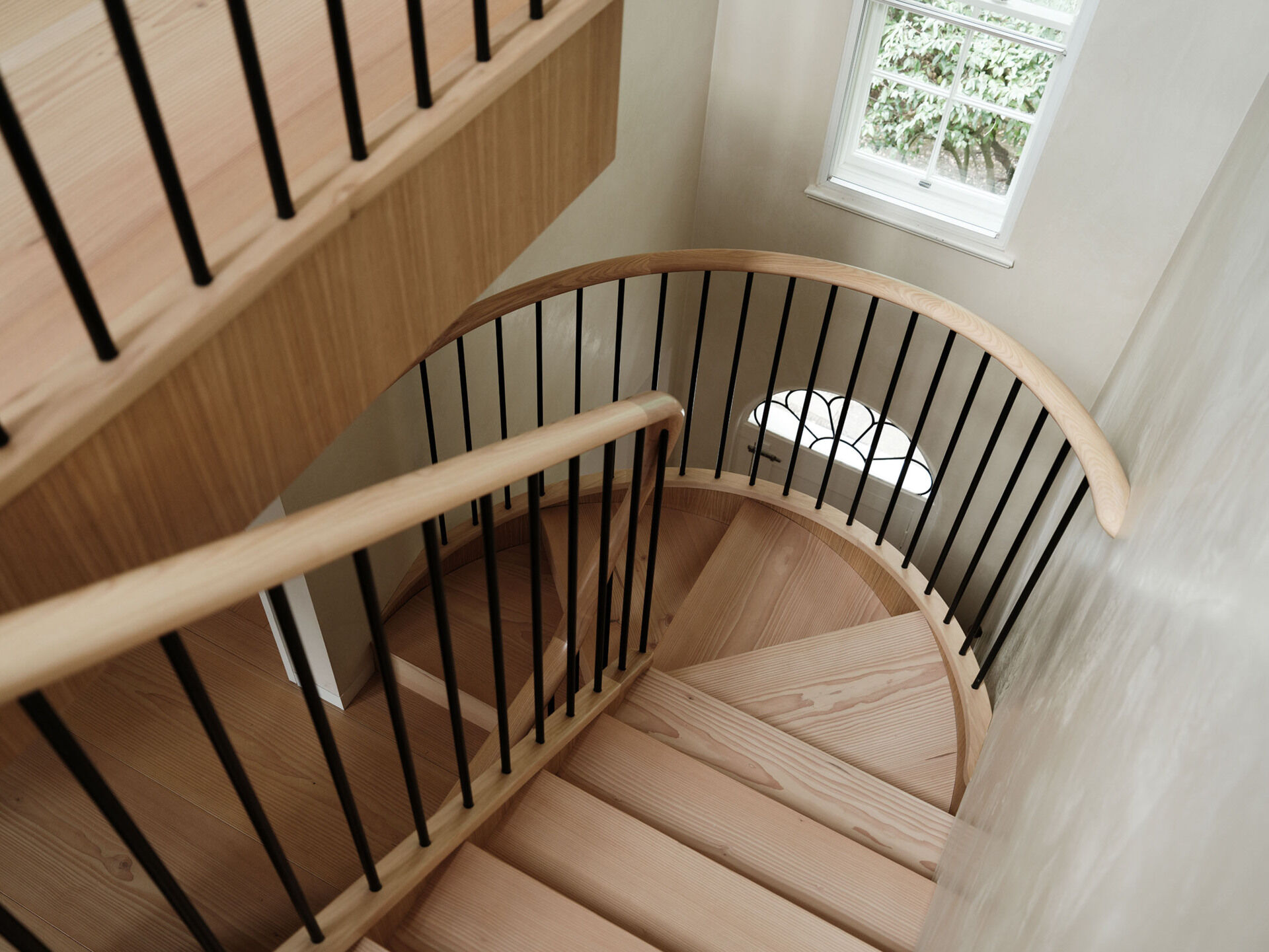 The staircase is the defining architectural element of the project. Designed as a bespoke feature with douglas fir treads and stone detailing, it rises through a three-story void. By repositioning the stair, the entrance becomes a double-height space, improving light distribution and creating a stronger connection between floors.