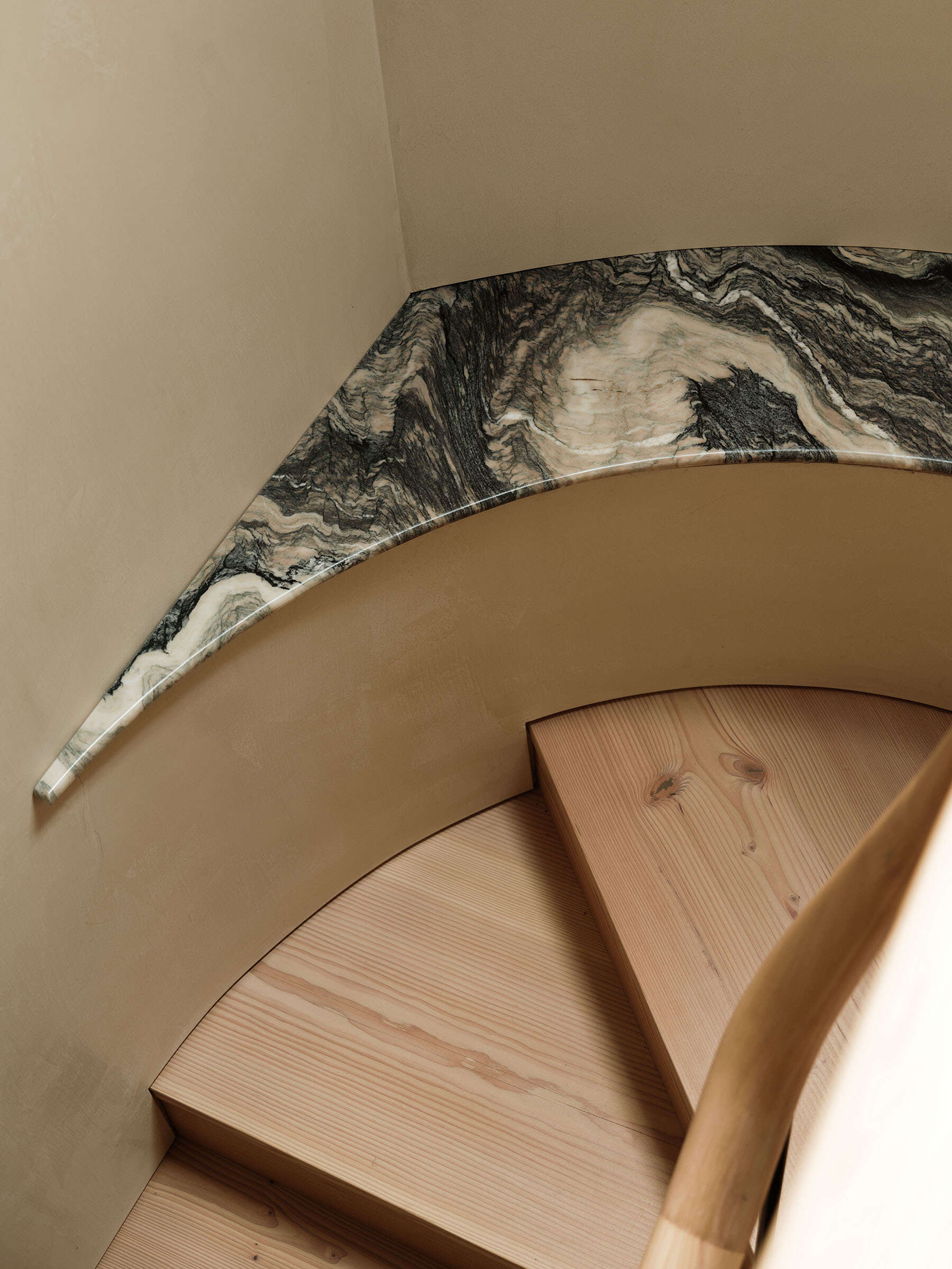 The staircase is the defining architectural element of the project. Designed as a bespoke feature with douglas fir treads and stone detailing, it rises through a three-story void. By repositioning the stair, the entrance becomes a double-height space, improving light distribution and creating a stronger connection between floors.