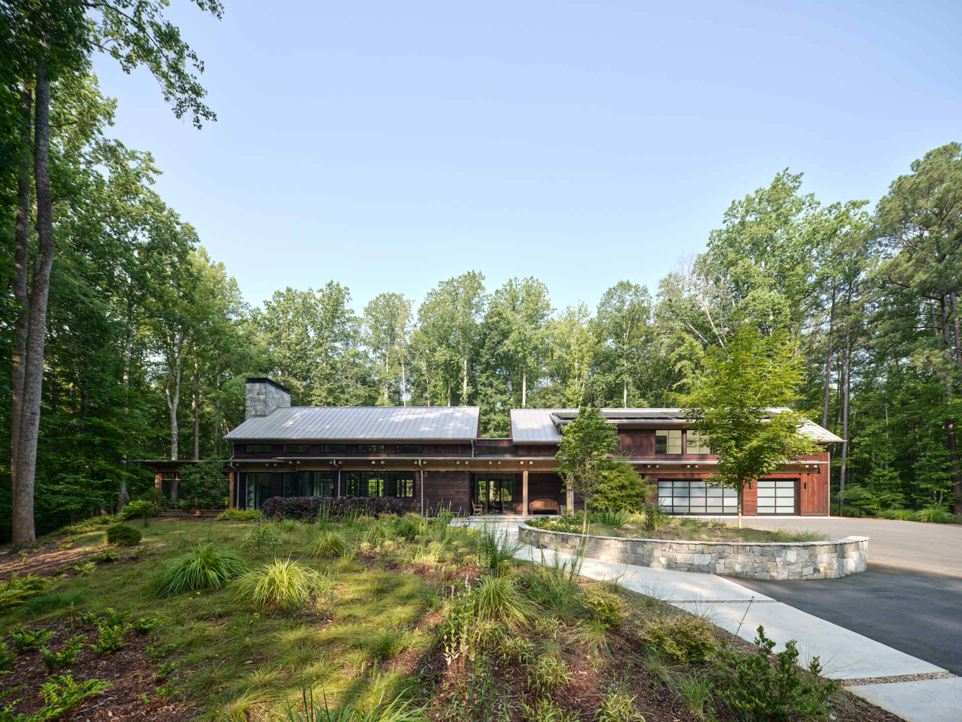 A winding forest driveway leads to this hilltop home in Duke Forest, where every arrival feels quiet and cinematic.