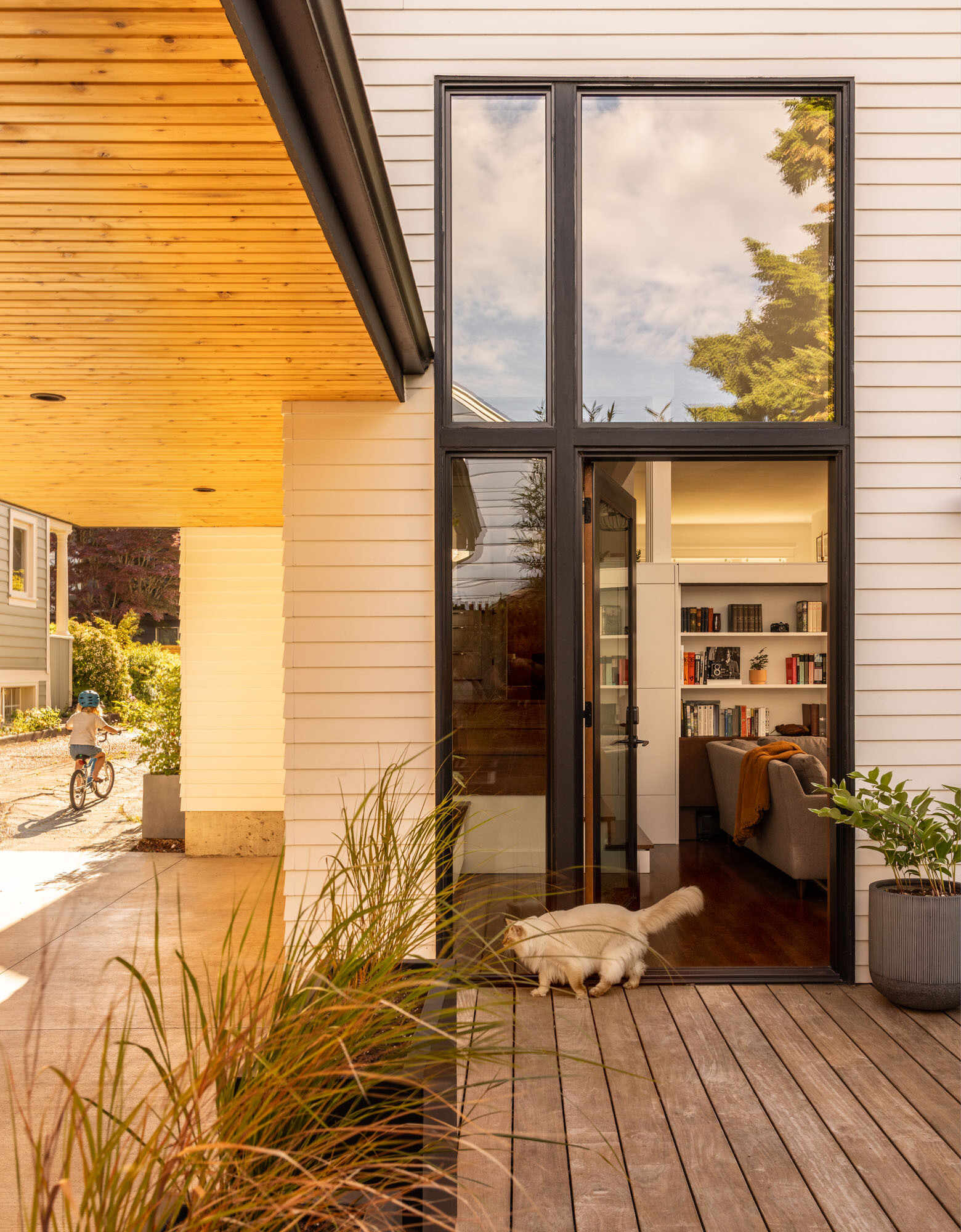 A compact backyard transforms into a layered outdoor retreat with a firepit, built-in seating, and a playful corner window connection.