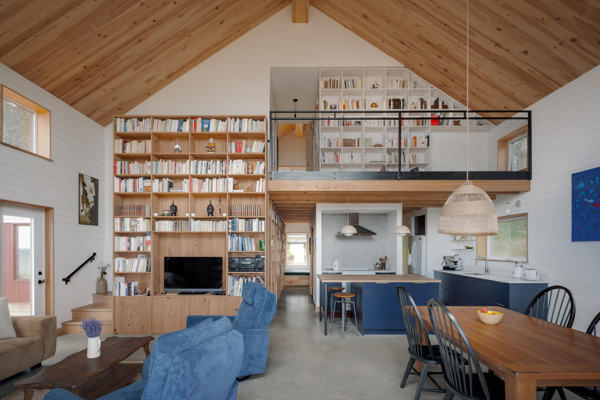 Una escalera situada a la izquierda de la estantería del salón conduce al ático, creando una clara conexión vertical entre las plantas. A medida que avanza hacia arriba, la perspectiva cambia y mira hacia el espacio habitable.