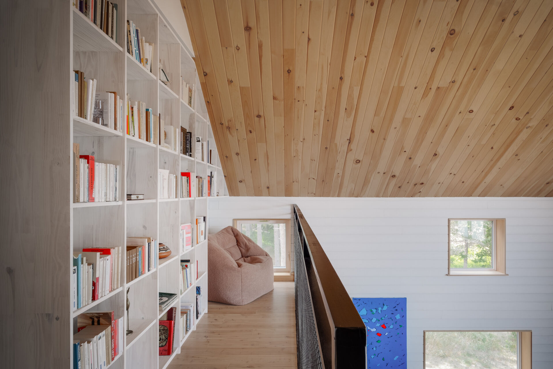 Las estanterías de pino personalizadas definen el loft, agregan calidez y crean un espacio de lectura.