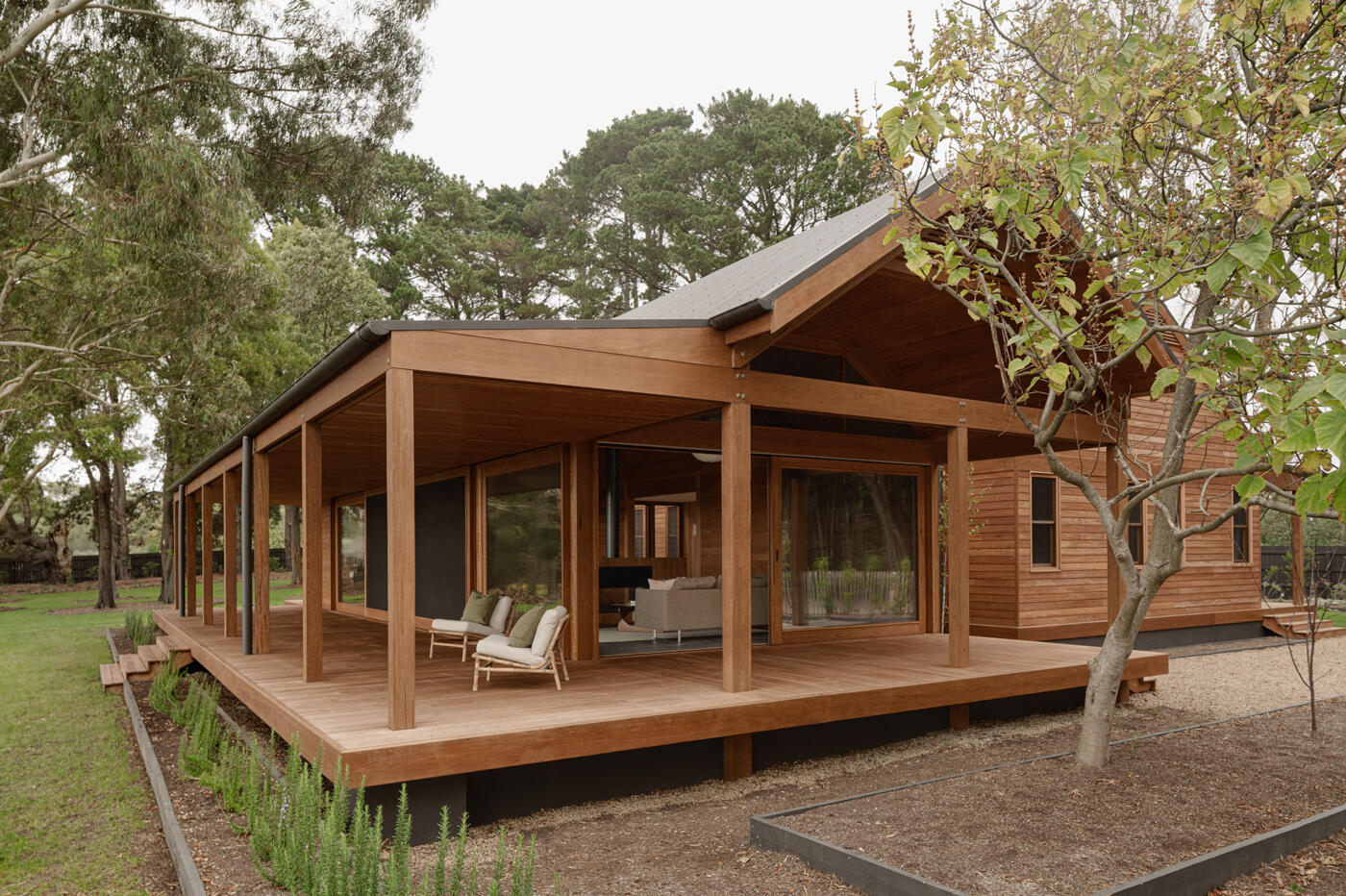 Verandas inspired by Australian vernacular architecture wrap the timber house, softening its scale and creating sheltered outdoor spaces that connect the home to its vineyard setting.