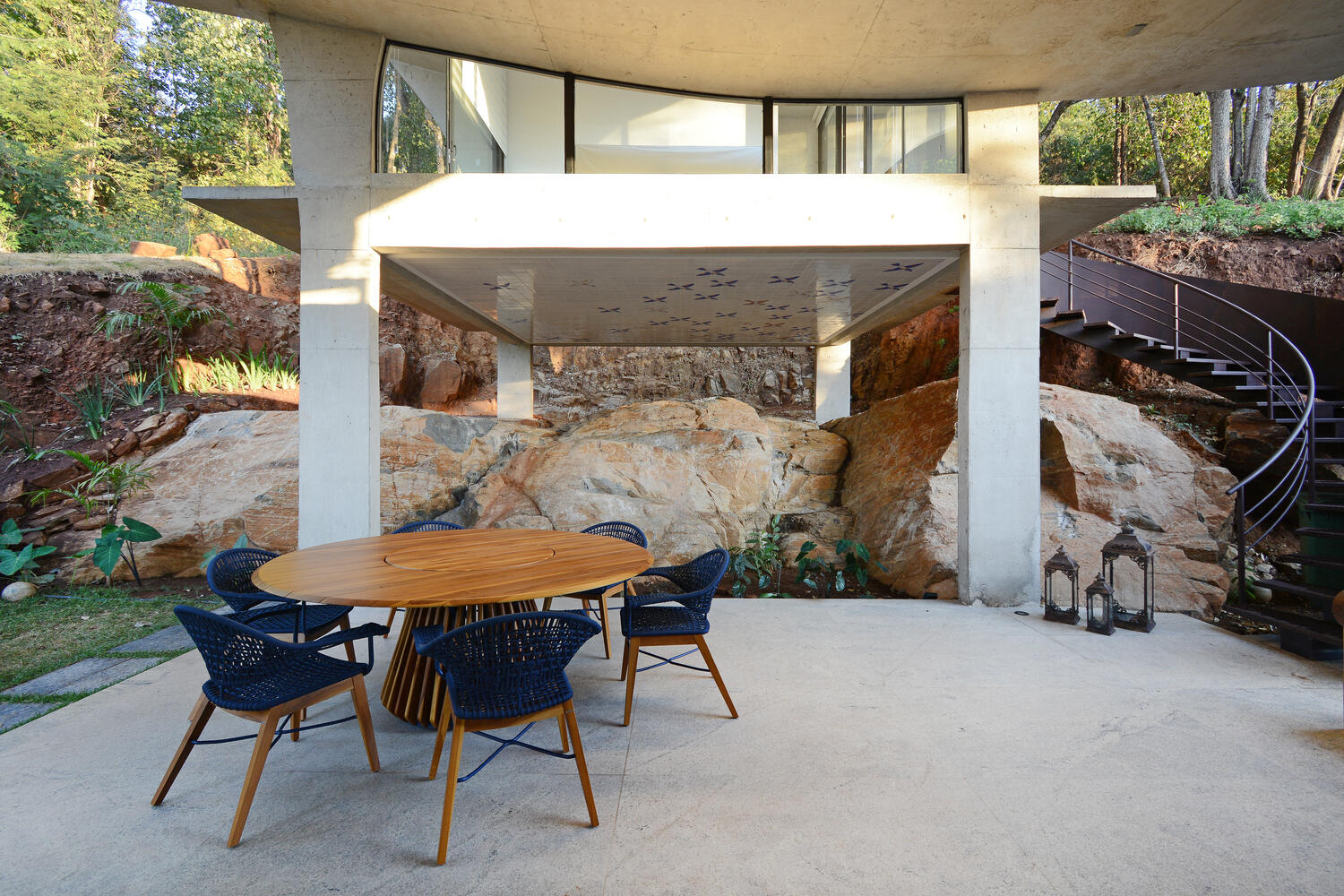 A covered patio with curved stairs extends the living space outdoors, continuing the architectural language of smooth concrete forms.