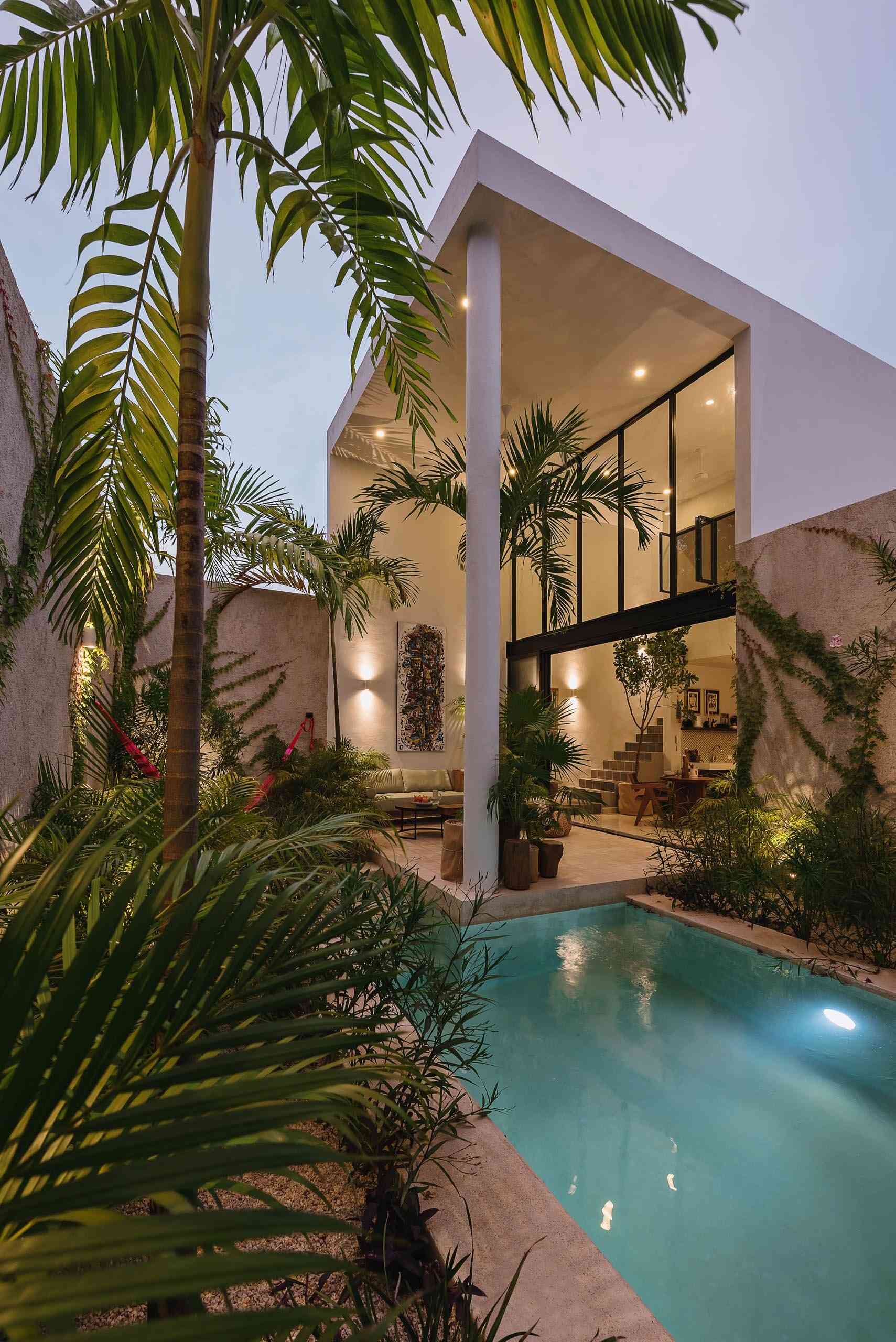 A compact courtyard pool surrounded by tropical plants and a textured stone wall creates a peaceful place to cool off on warm days.