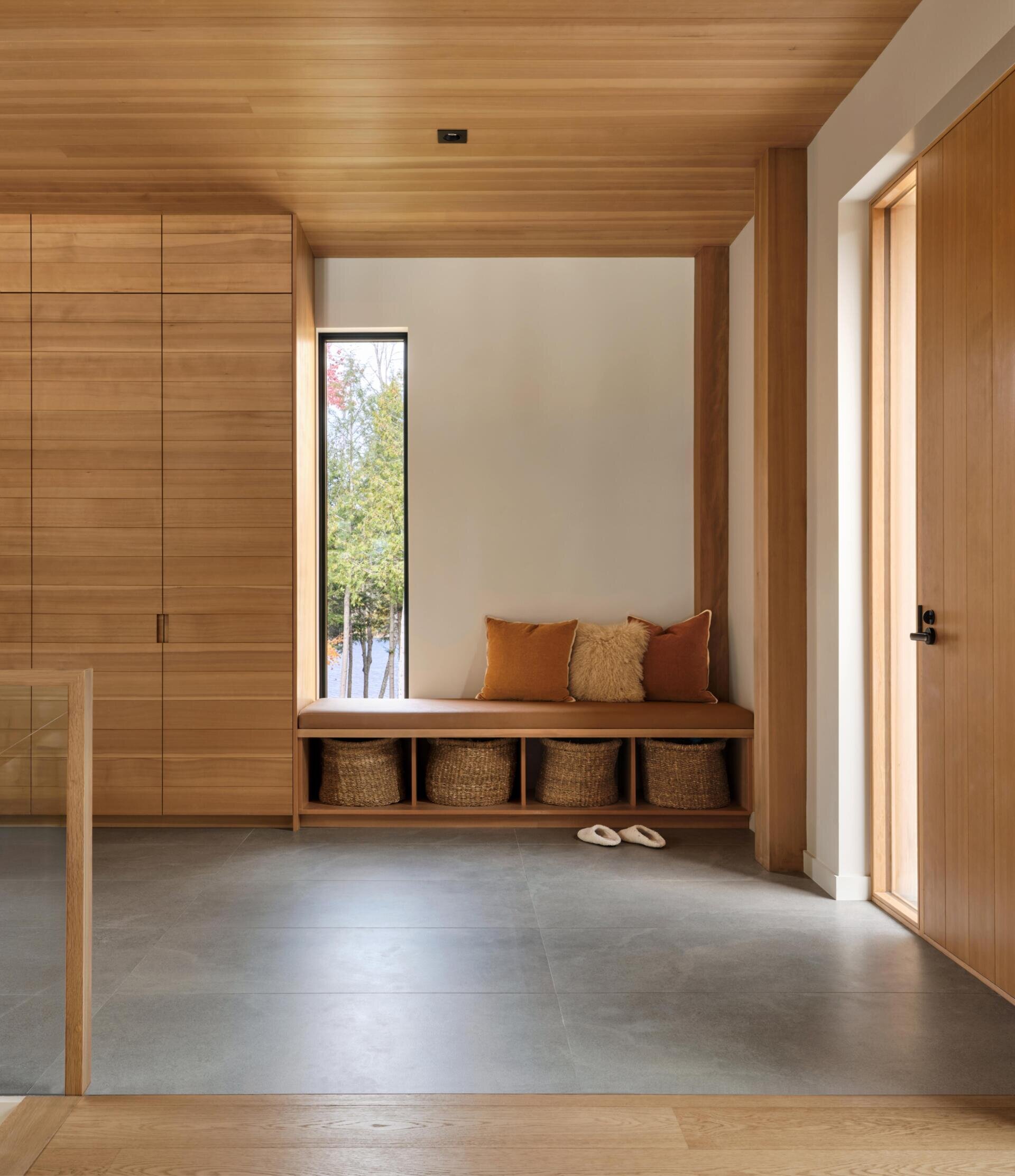 A calm, grounded entry with stone-inspired tiles and warm wood finishes sets the tone for this forest cottage, creating a subtle connection to the rugged landscape outside.
