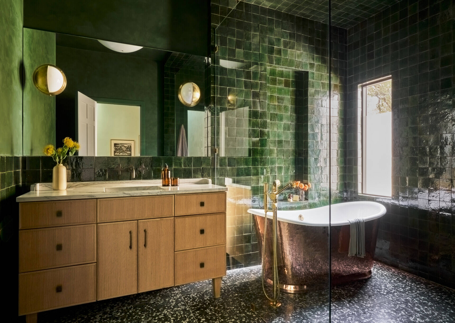 In the bathroom, forest green zellige tiles and a copper tub create a rich, immersive space with bold contrast.