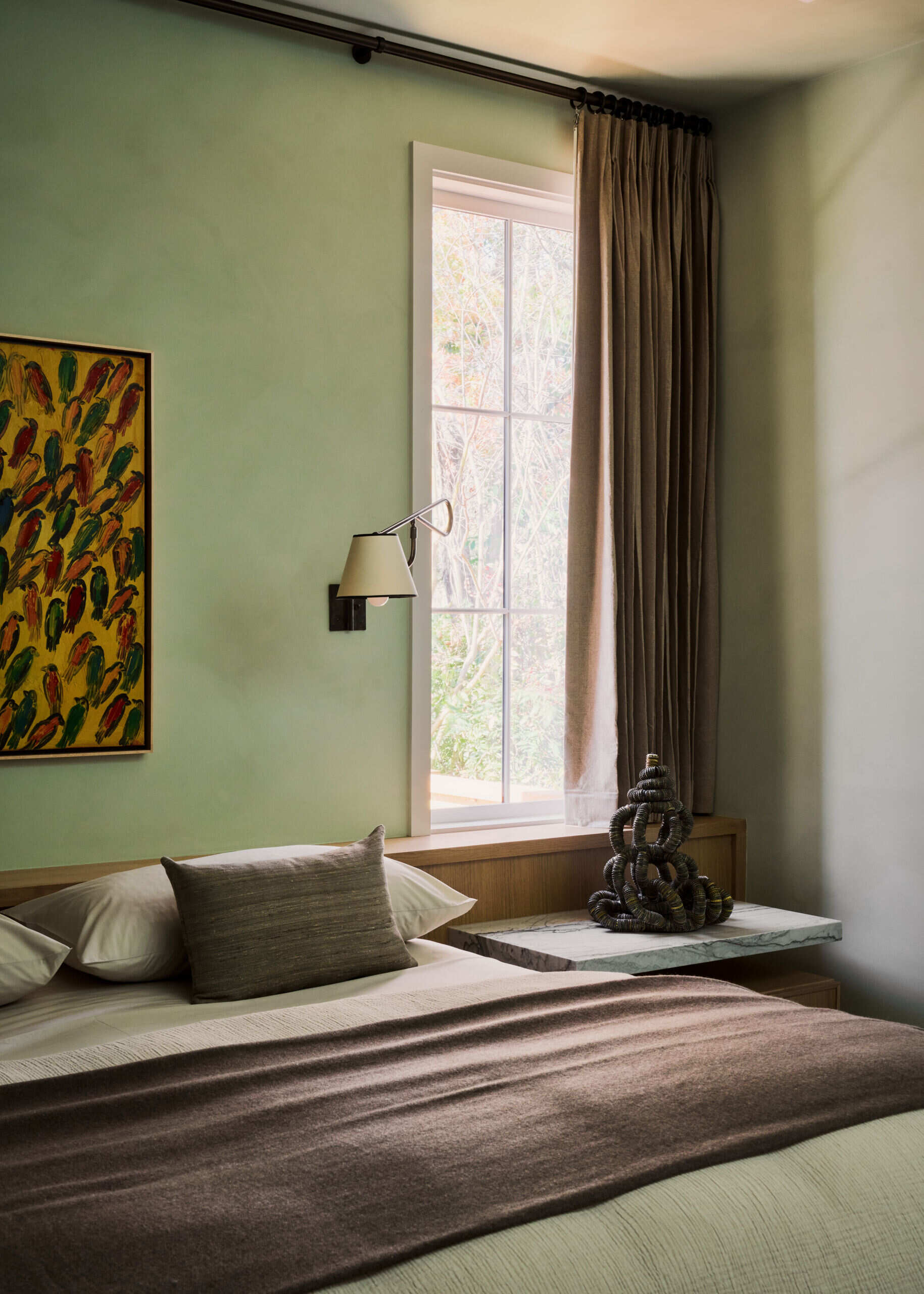 In the bedroom, deep greens and layered materials create a calm, immersive retreat away from the home’s brighter spaces.