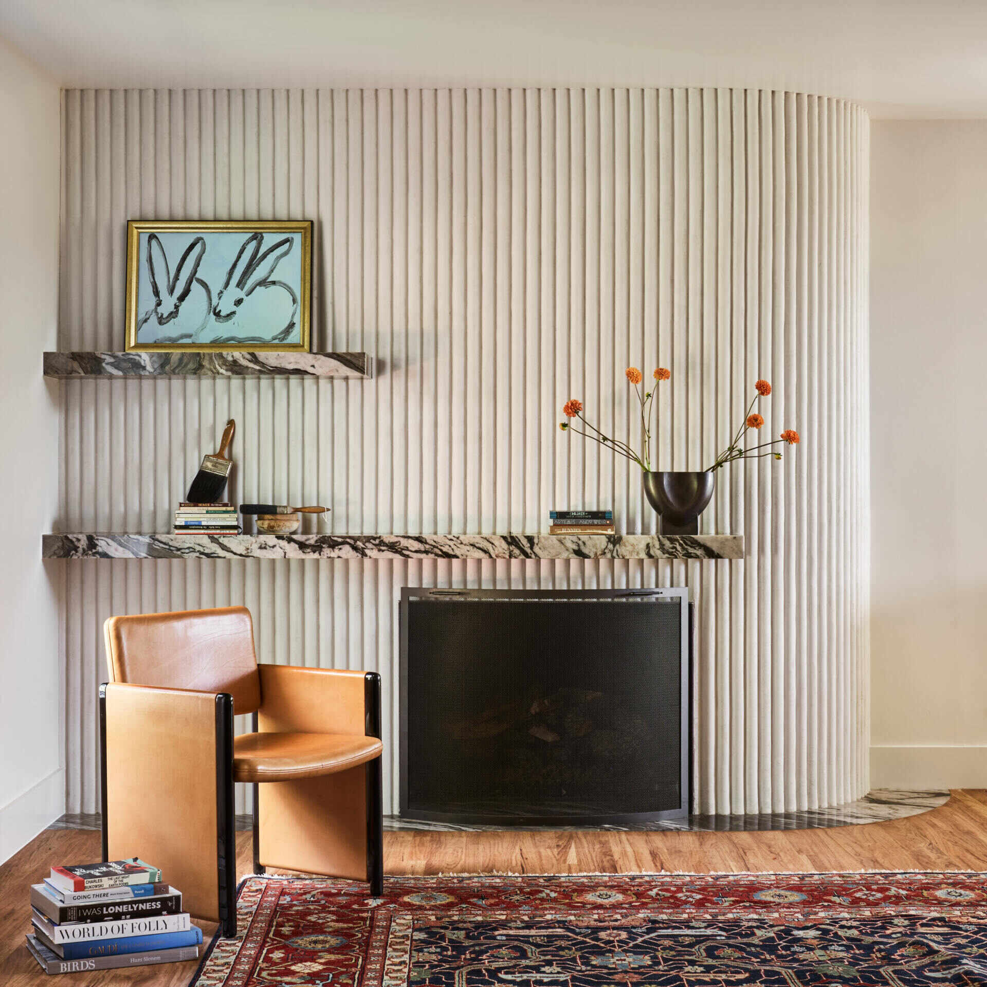 In the living room, a curved plaster fireplace wall adds soft texture and sculptural warmth to a relaxed, light-filled space.