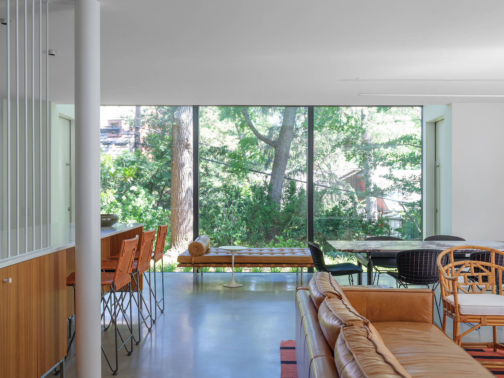 Along the rear wall, expansive glass and doors frame views of the wooded yard and draw natural light deep into the home.