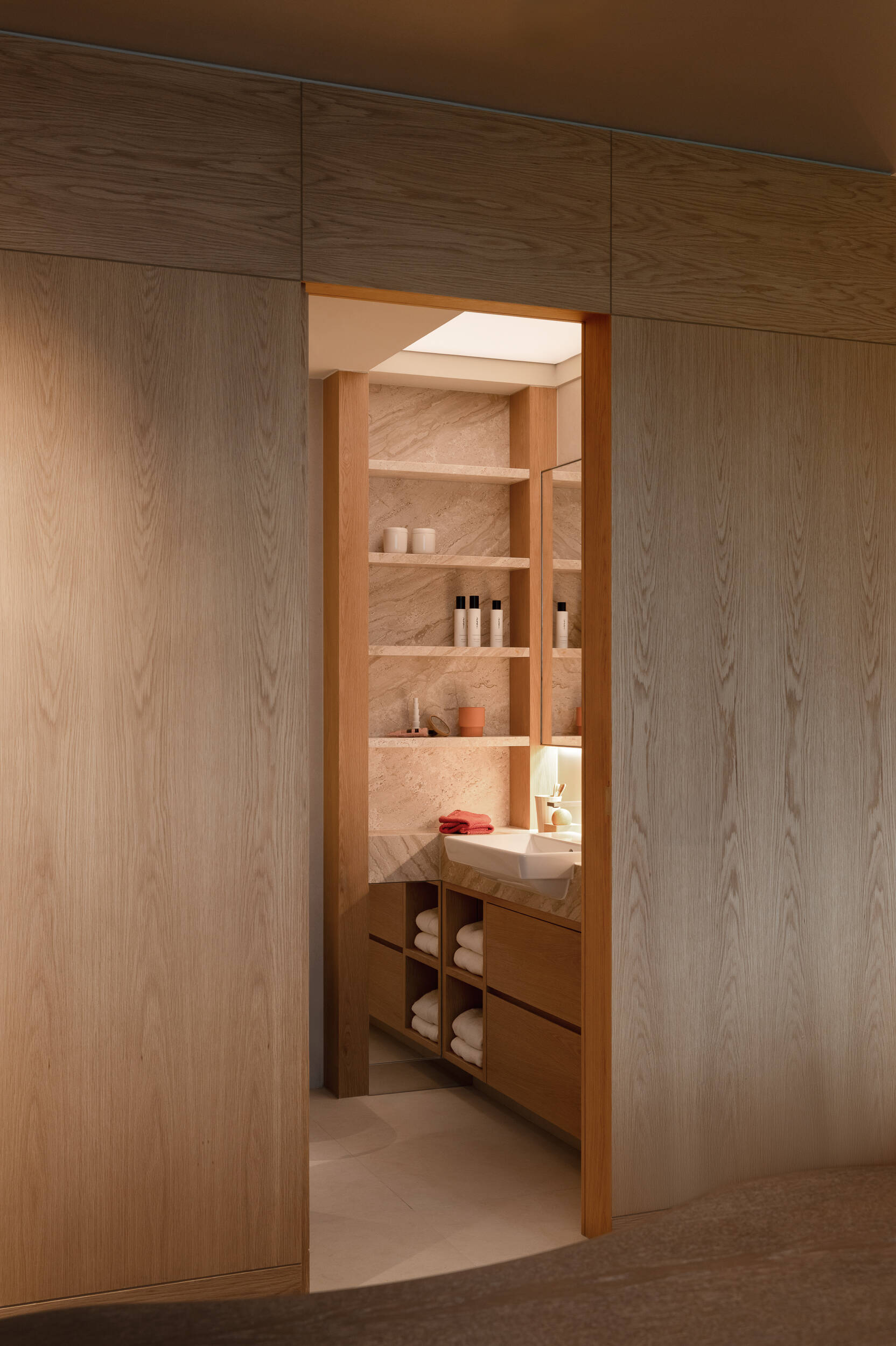 In the guest bathroom, a luminous ceiling mimics daylight, transforming a dark space into a softly glowing, serene environment.